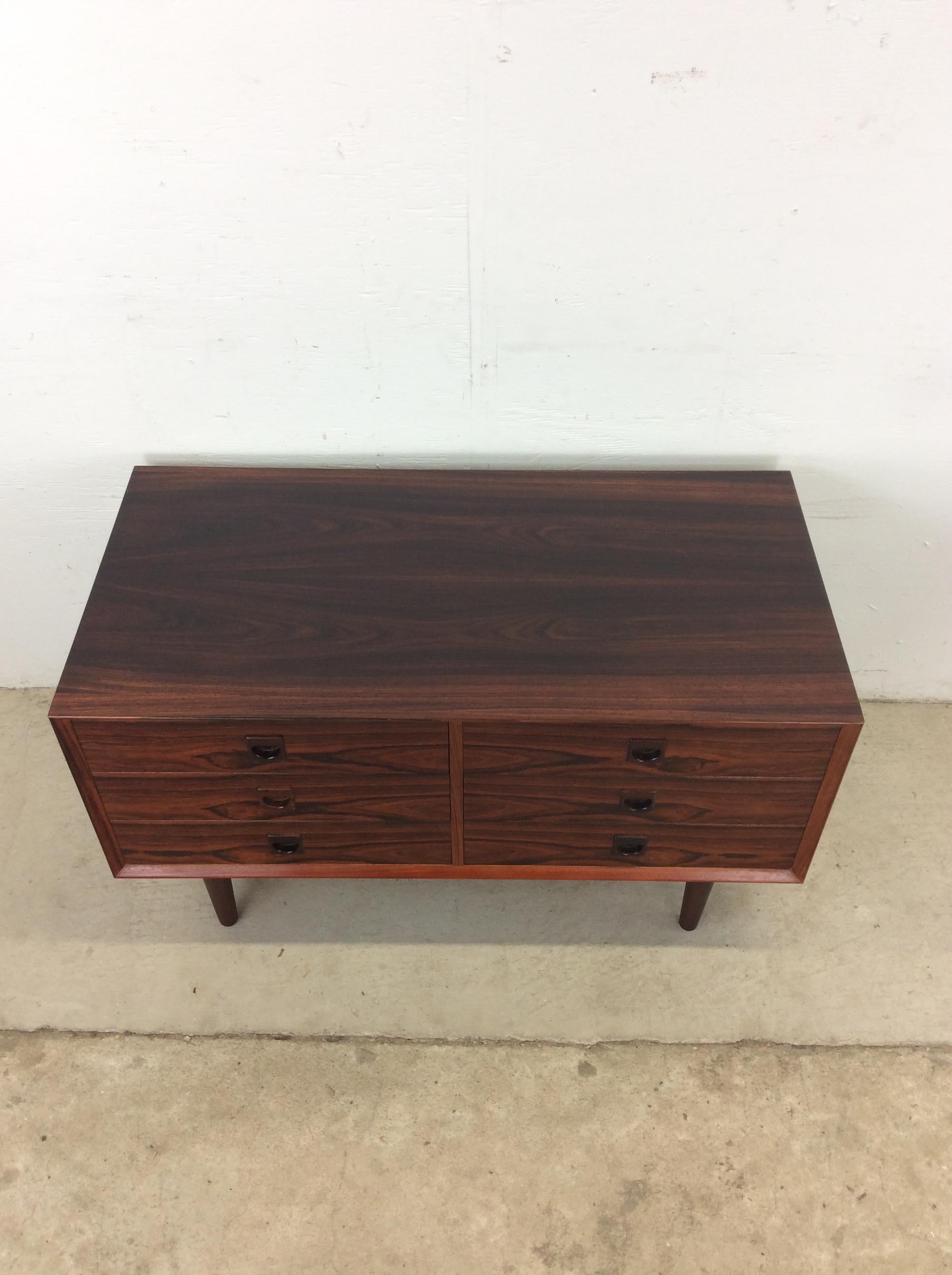 This Danish Modern petite chest of drawers features hardwood construction, rosewood veneer with original finish, six dovetailed drawers with felt lining and carved pulls, and tall tapered legs. 

Dimensions: 39.5w 20d 22.25h   

Condition notes: