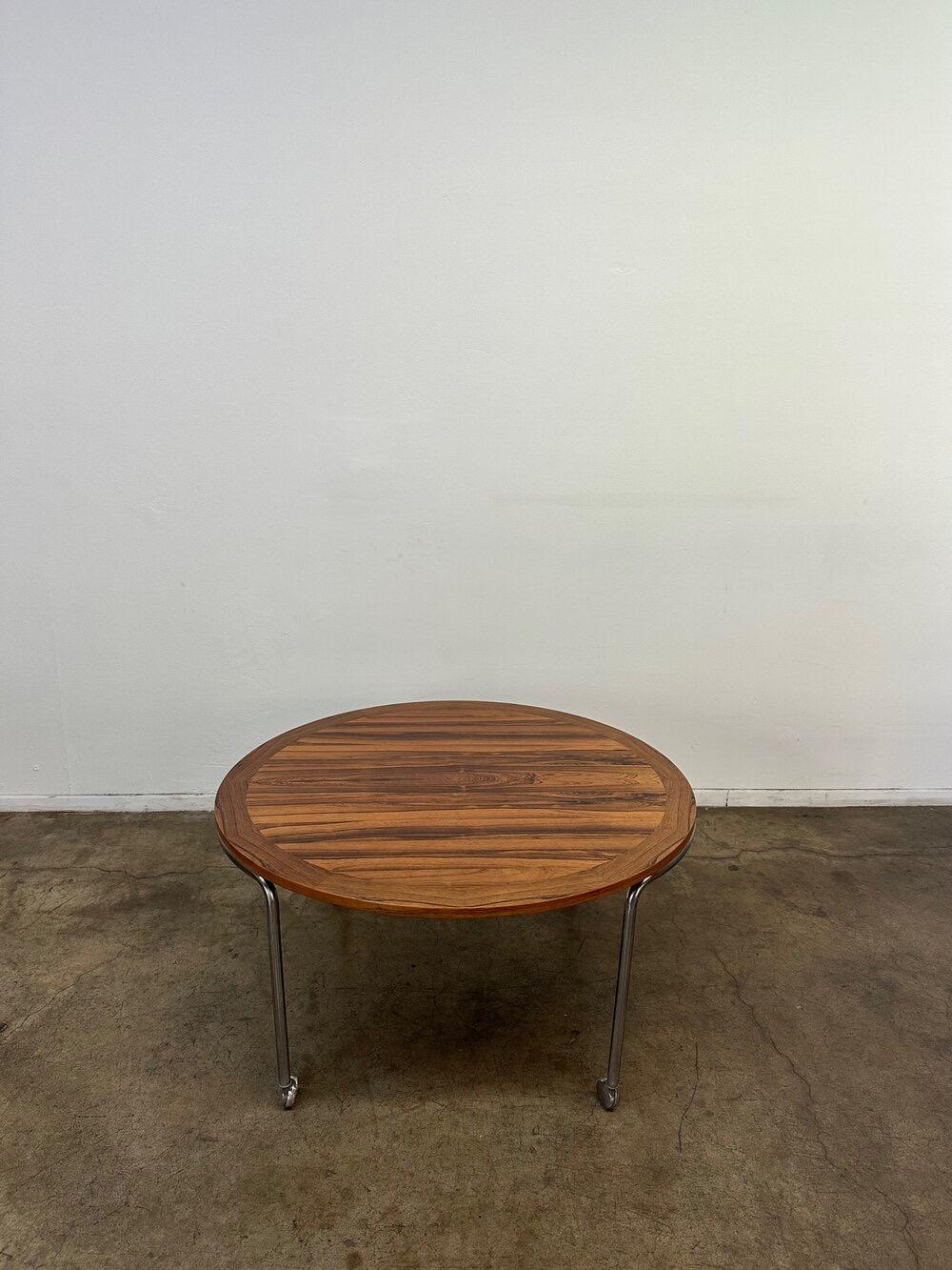 Vintage round Rosewood coffee table with curved chrome frame and castors. Rosewood has been refinished. Item is fully functional and structurally sound. 