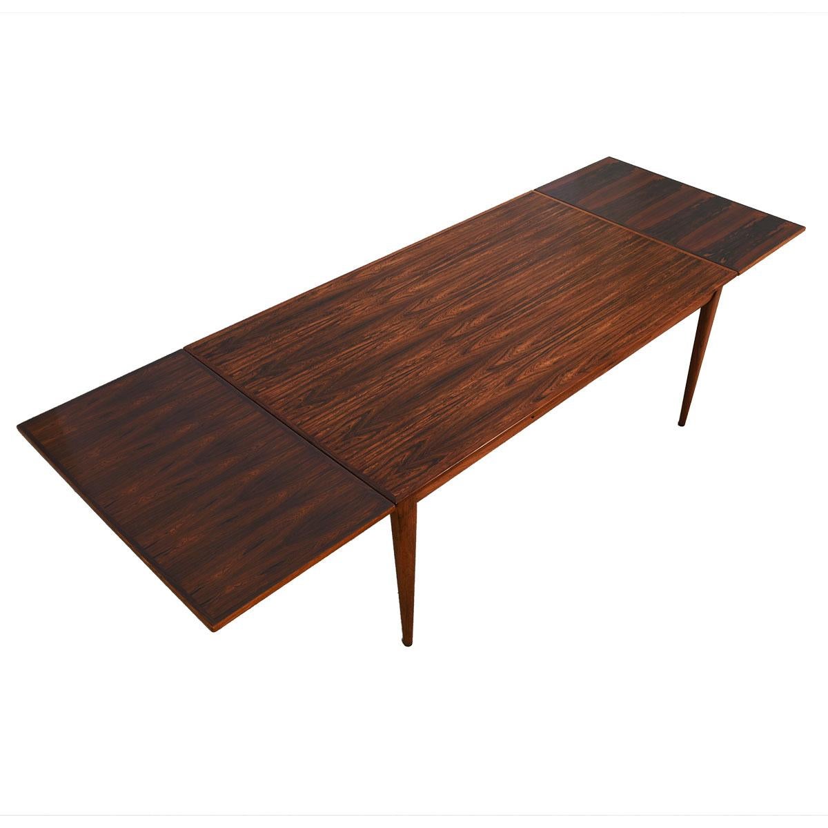 Dramatic and stunning grain on this danish modern dining table enhances its extraordinary length.

A wonderful extra-large danish modern rosewood dining table.
Two self-storing leaves pull out from under the table’s top, each adding 22.75