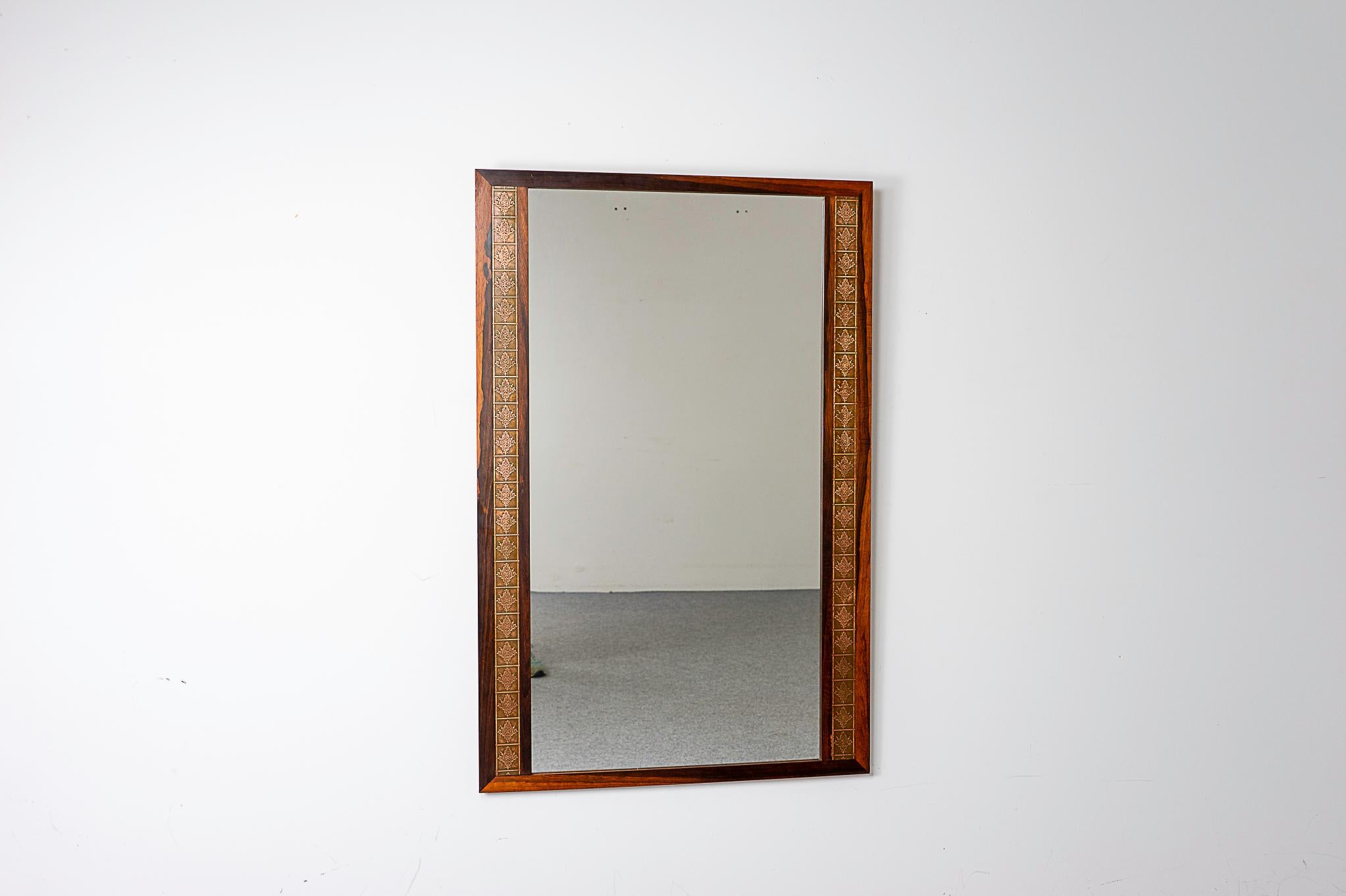 Dänischer Spiegel aus Rosenholz und Kupfer, ca. 1960. Die perfekte Ergänzung für jedes Interieur, besonders in kleinen Wohnungen, Eigentumswohnungen und Lofts, wo der Platz knapp sein kann. Dekorative geprägte Metallverzierungen auf beiden