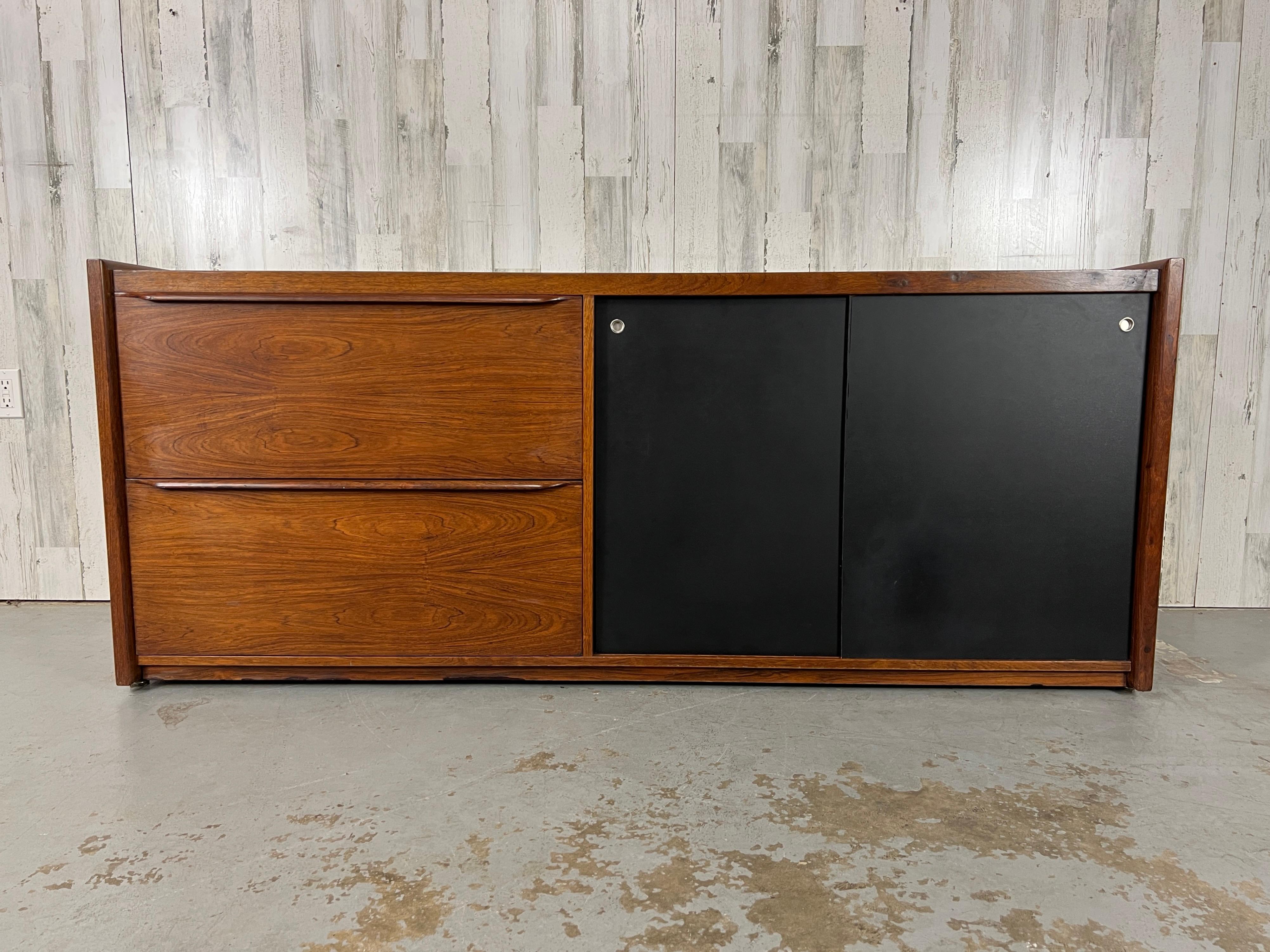 Classic figural rosewood Danish Modern credenza with black masonite sliding doors.
There is a shelf behind the sliding doors next to two file drawers for origination.
The back is also finished, please see pictures.
Original finish.