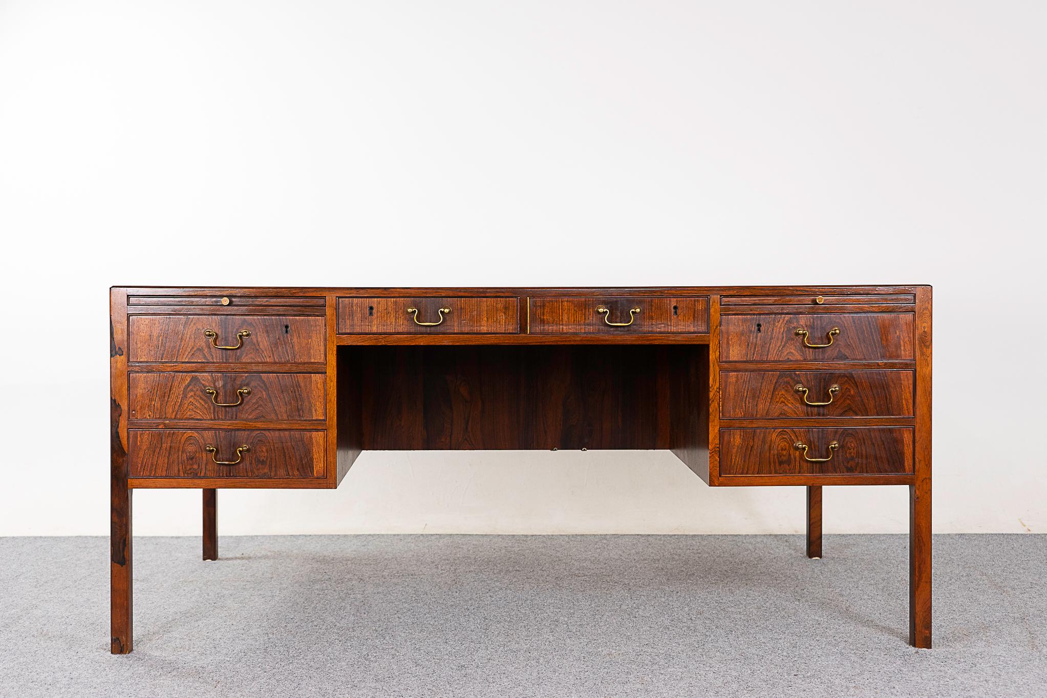 Rosewood mid-century desk by Ole Wanscher, circa 1950's. Exceptional bookmatched veneer top and drawer faces. Darling metal finger pulls and and extending surfaces, open rear bookcase and locking storage drop down compartments. Quality through and