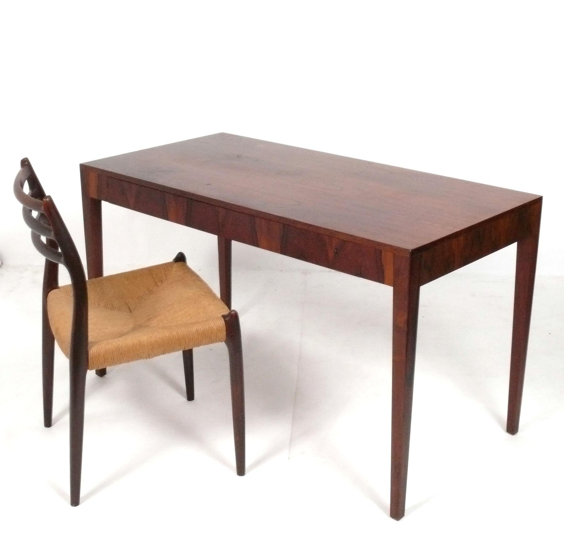 Clean Lined Danish Modern Rosewood Desk, designed for Riis Antonsen, and Rosewood Desk Chair designed by Neils Moller, both from Denmark, circa 1960s. Branded with manufacturer's name underneath the desk. Beautiful graining to the rosewood