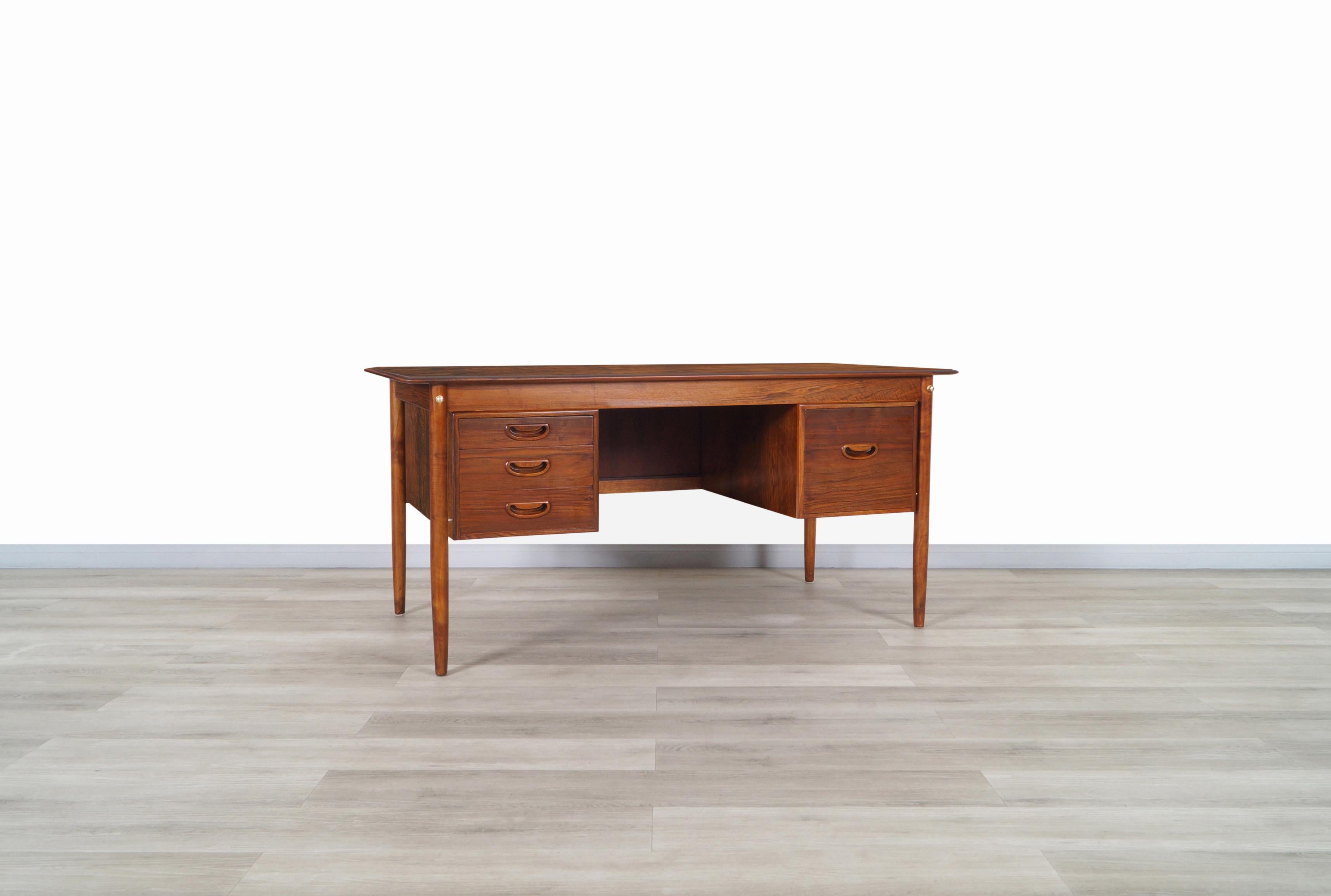 Amazing Danish modern rosewood desk manufactured in Denmark, circa 1960s. Features three dovetail drawers and a file drawer where the aesthetic and Minimalist design of the handles in each drawer stand out. The structure of the desk is extremely