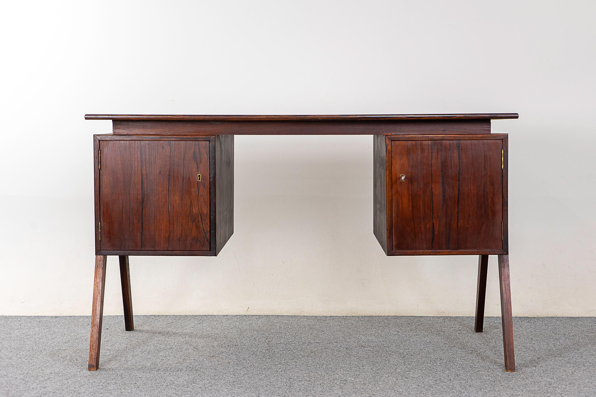 Danish Modern rosewood desk, circa 1960's. Writing desk finished on both sides, this desk can be placed in the center of a room and look fantastic on all sides. This writing desk features a clean uncluttered design with splayed legs and beautiful