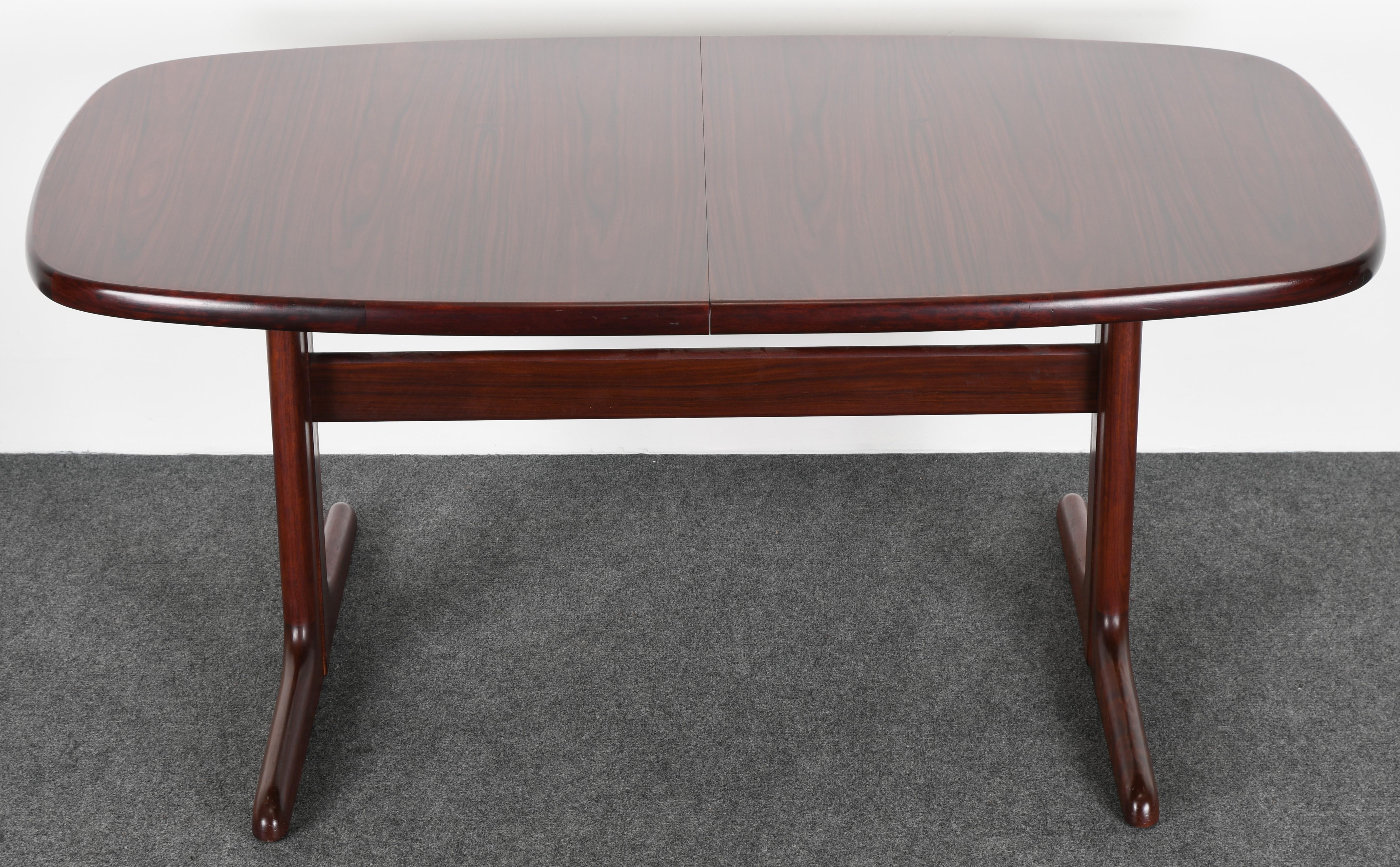 A gorgeous Danish modern rosewood dining room table by Skovby Mobelfabrik A/S. This table has two matching leaves that store underside, as shown in images. It is in very good condition with age appropriate wear. Several small imperfections, not