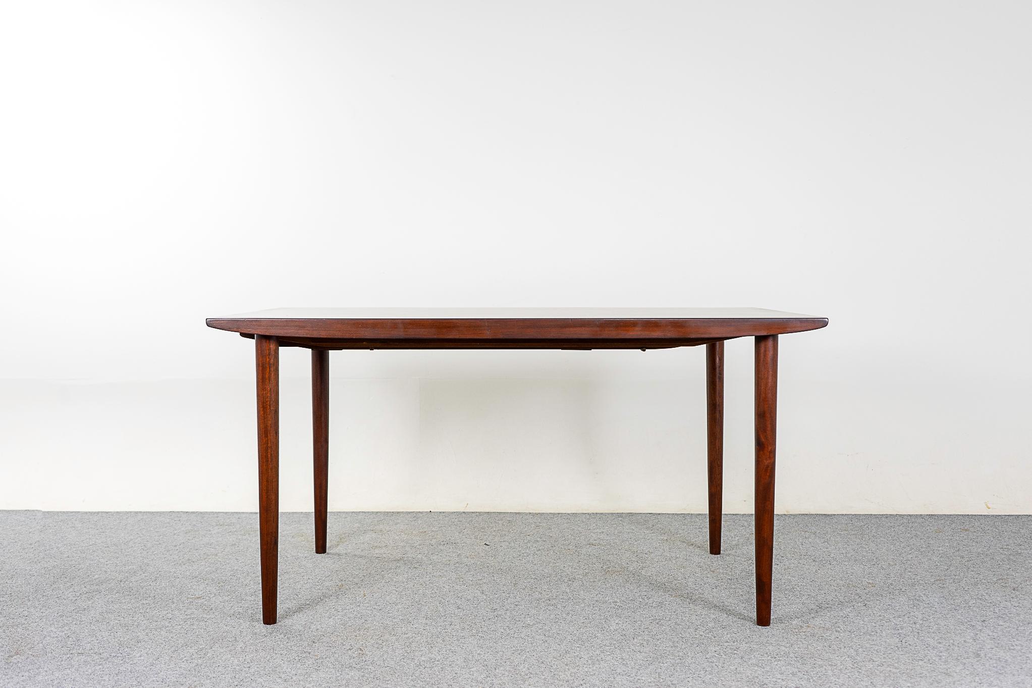 Rosewood Danish dining table, circa 1960's. Top is framed in solid wood edge trim,  center panels feature highly figured veneer with book-matched grain. Contrasting black leaves are conveniently stored under the table. 

55