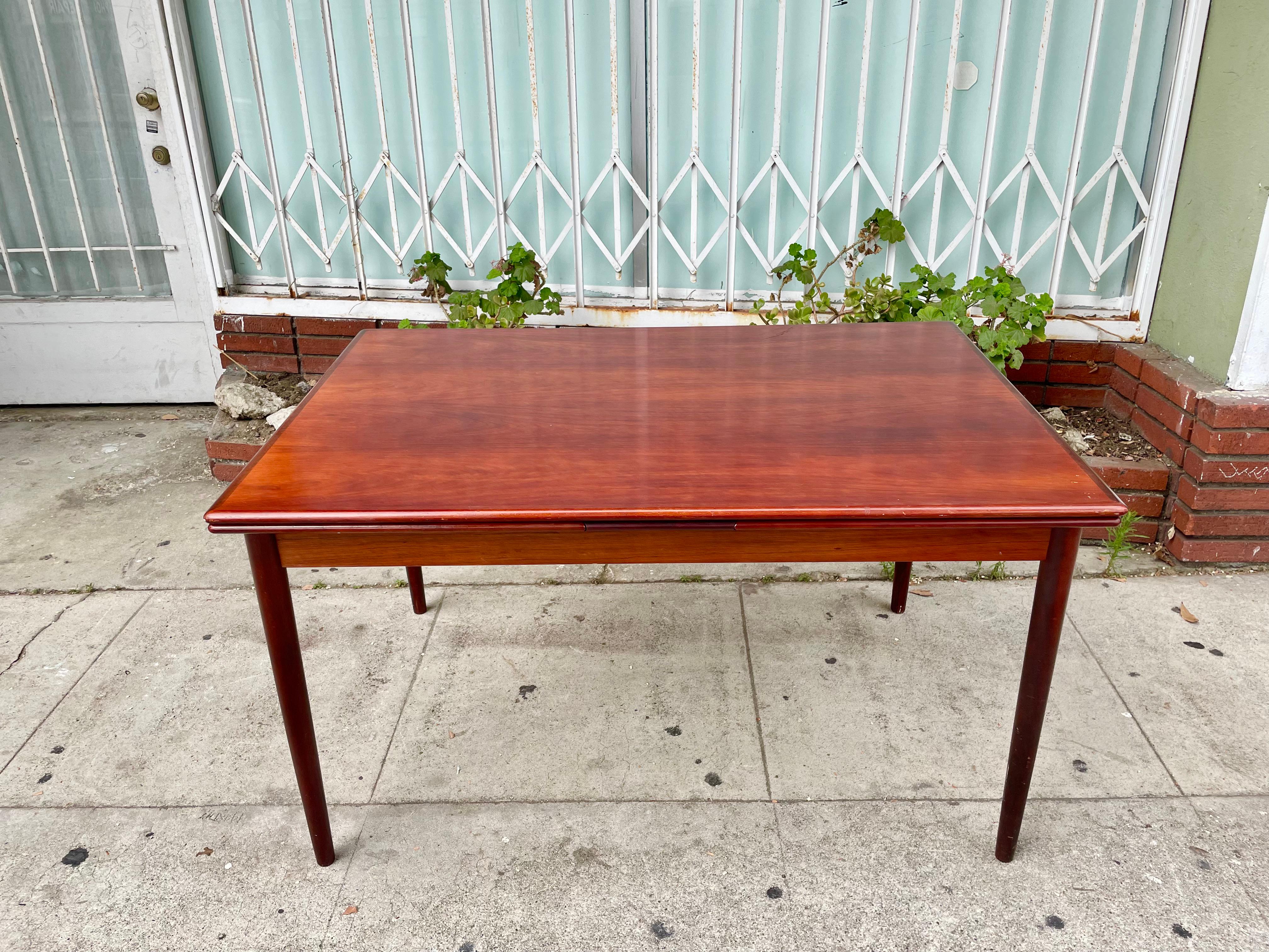 Danish modern rosewood extending dining table manufactured by AM Mobler in Denmark. This vintage dining table was built with the highest quality of rosewood. It features a versatile and easy-to-use design. If you want to expand the dining table, you
