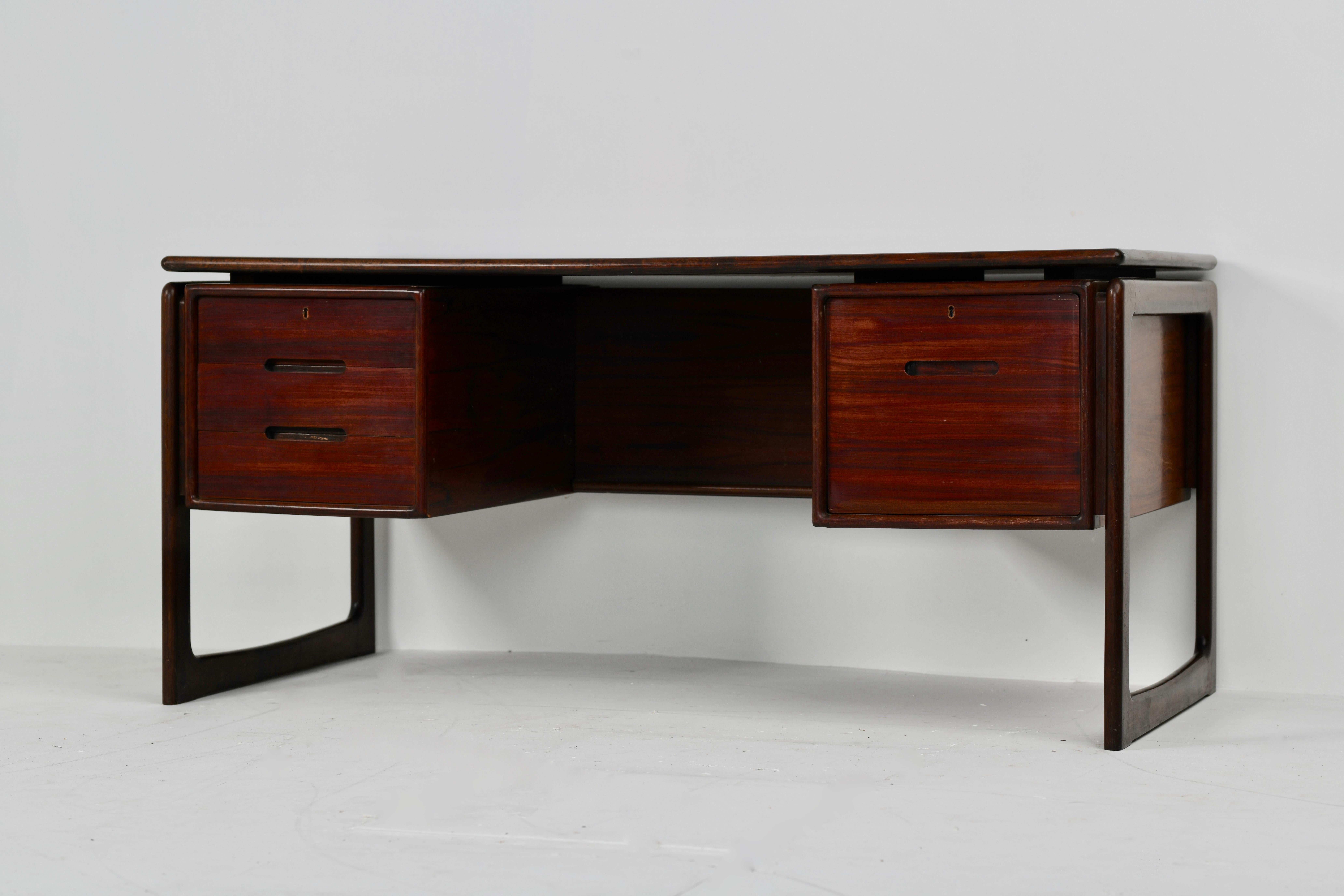 Stylish modern executive desk designed and manufactured in Denmark by Drylund circa 1960s. This striking Danish Modern design features a rosewood frame and three spacious drawers on the left side, a file cabinet on the right, and an open back with