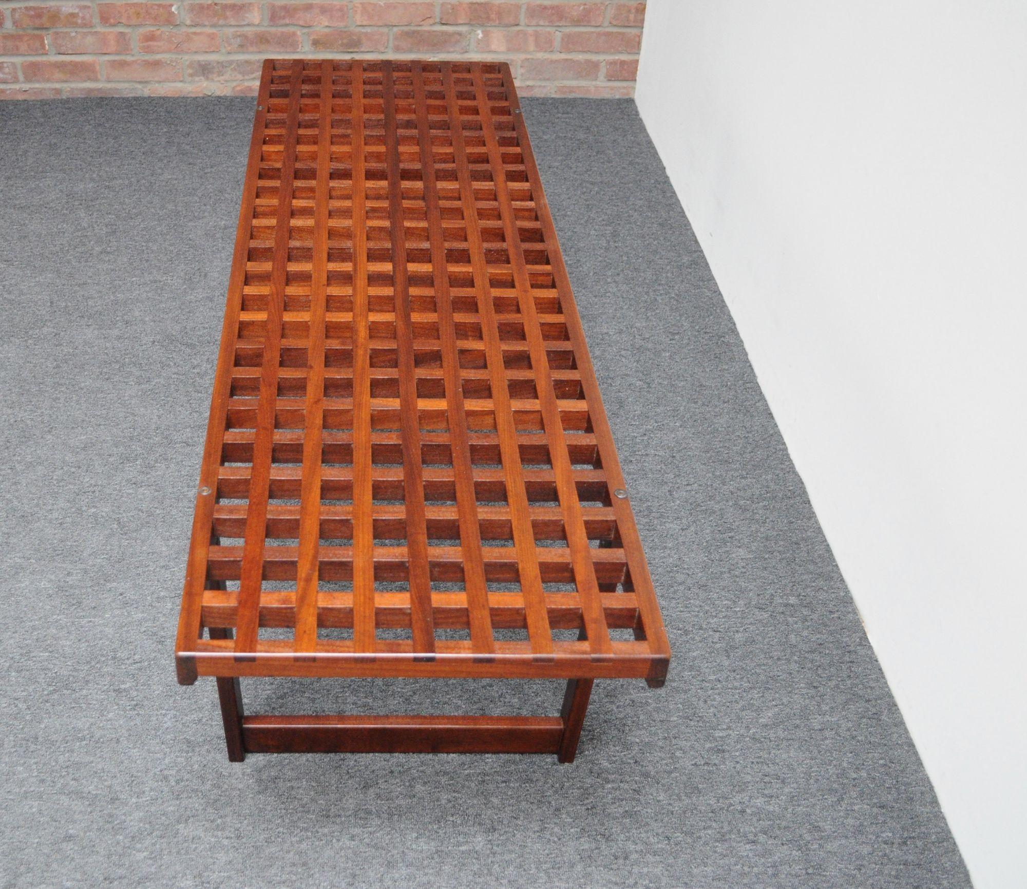 Danish Modern 'grid' coffee table/bench by Peter Løvig Nielsen boasting rich wood tone and vivid grain (ca. 1960s, Denmark).
Composed of a rosewood slatted lattice surface supported by two deeply sculpted rosewood bases.
Newly refinished condition;