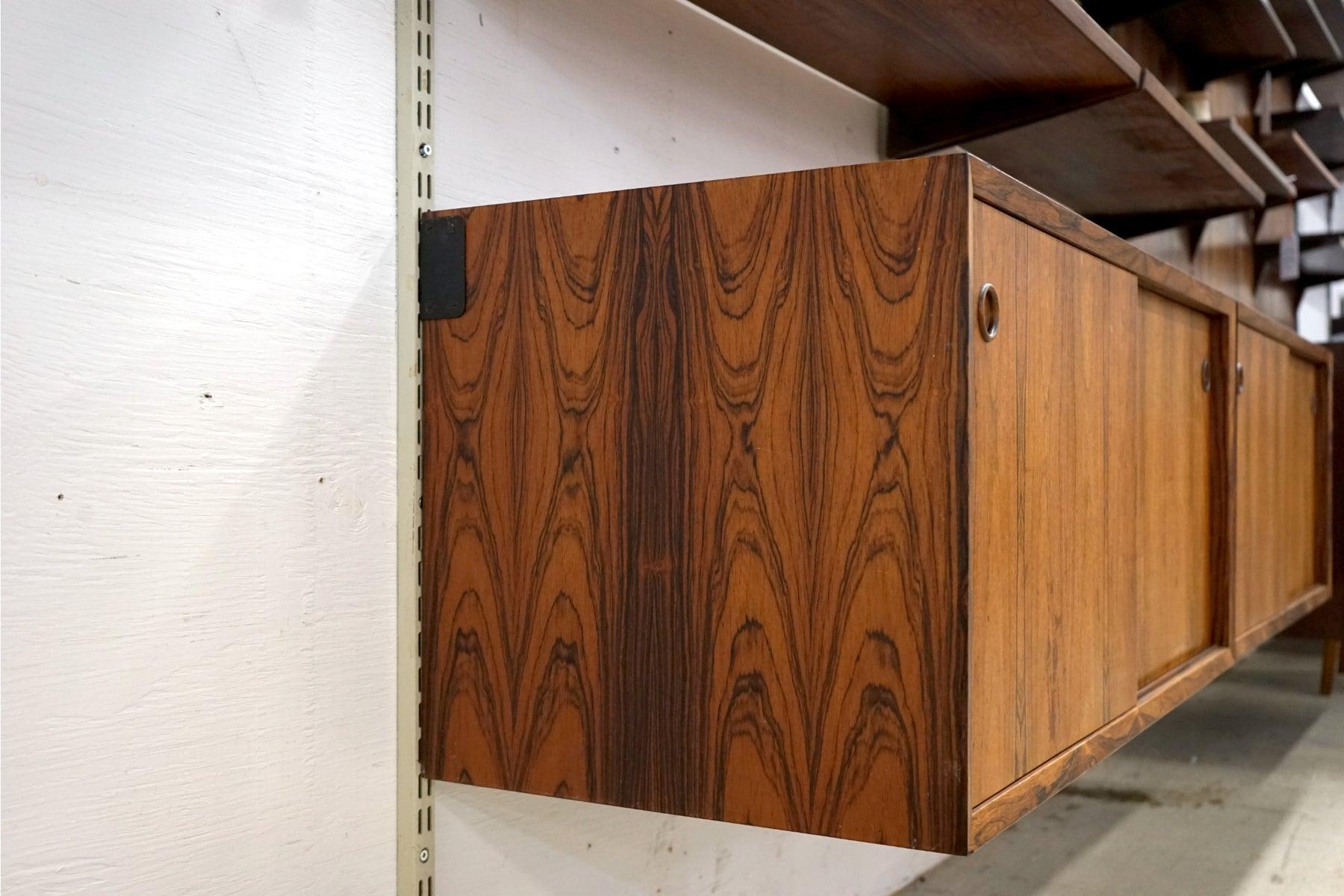 Rosewood wall system, circa 1960's. Modular cabinetry and shelving make this versatile wall system the perfect solution for home or office, wherever space is limited but function is a high priority. This fantastic wall system features solid wood