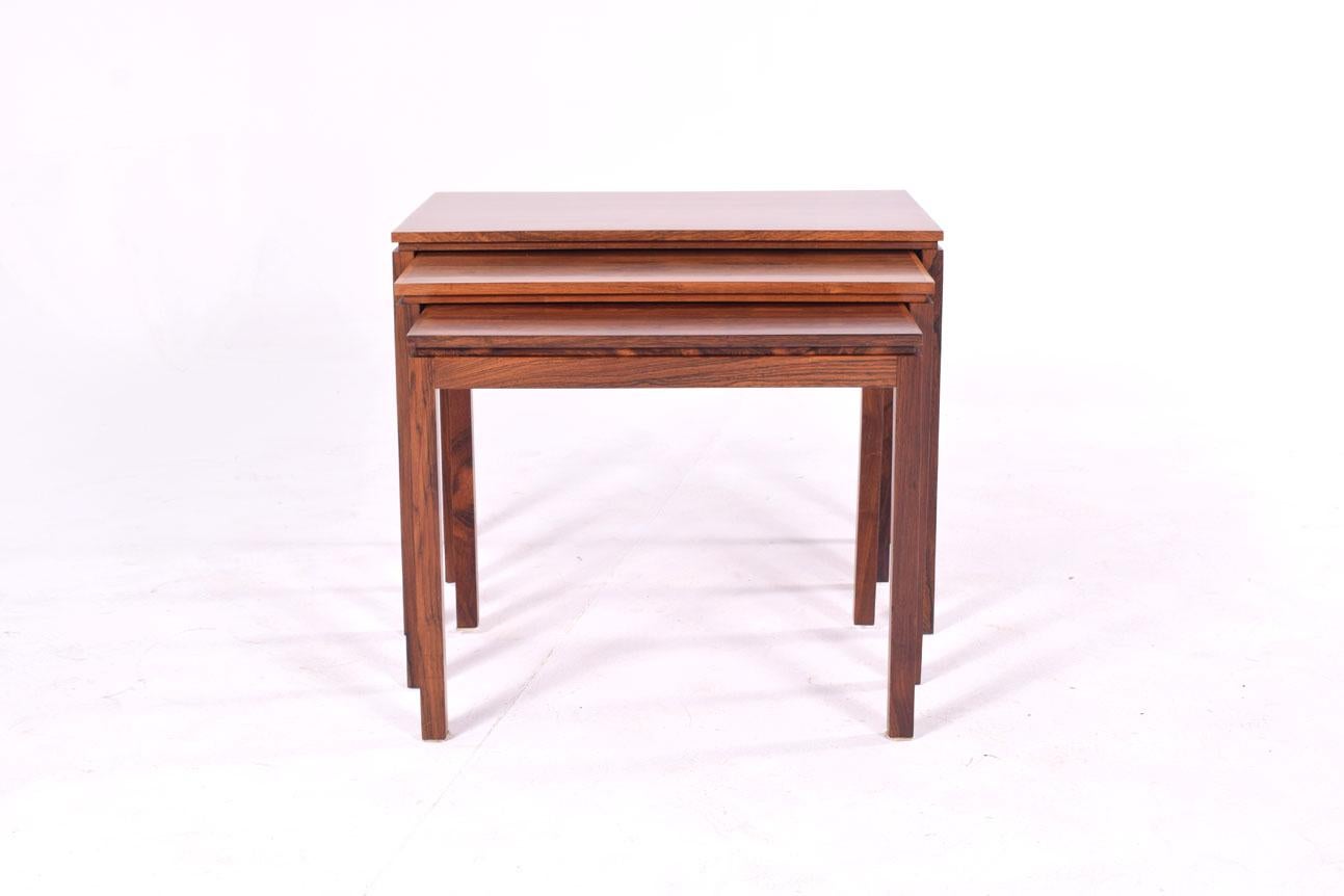 Set of three Danish rosewood nesting tables of ascending size. Fine construction, solid rosewood bolt-on legs and old growth, fiery, grain are just a few notable qualities. Seamless joinery and Classic Danish design gives these 1960s stacked tables