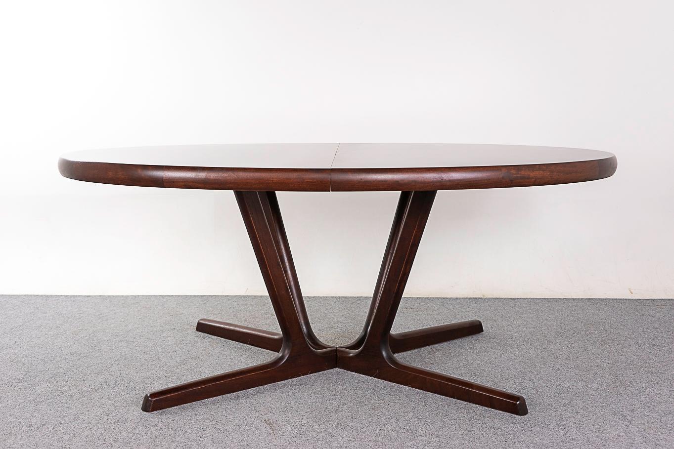 Rosewood mid-century dining table, circa 1960's. Oval top rests upon sculpted solid wood pedestal. Base extends along with the top, increasing stability when expanded. Highly figured veneer and curved solid edges. Robust, yet elegant!   

68