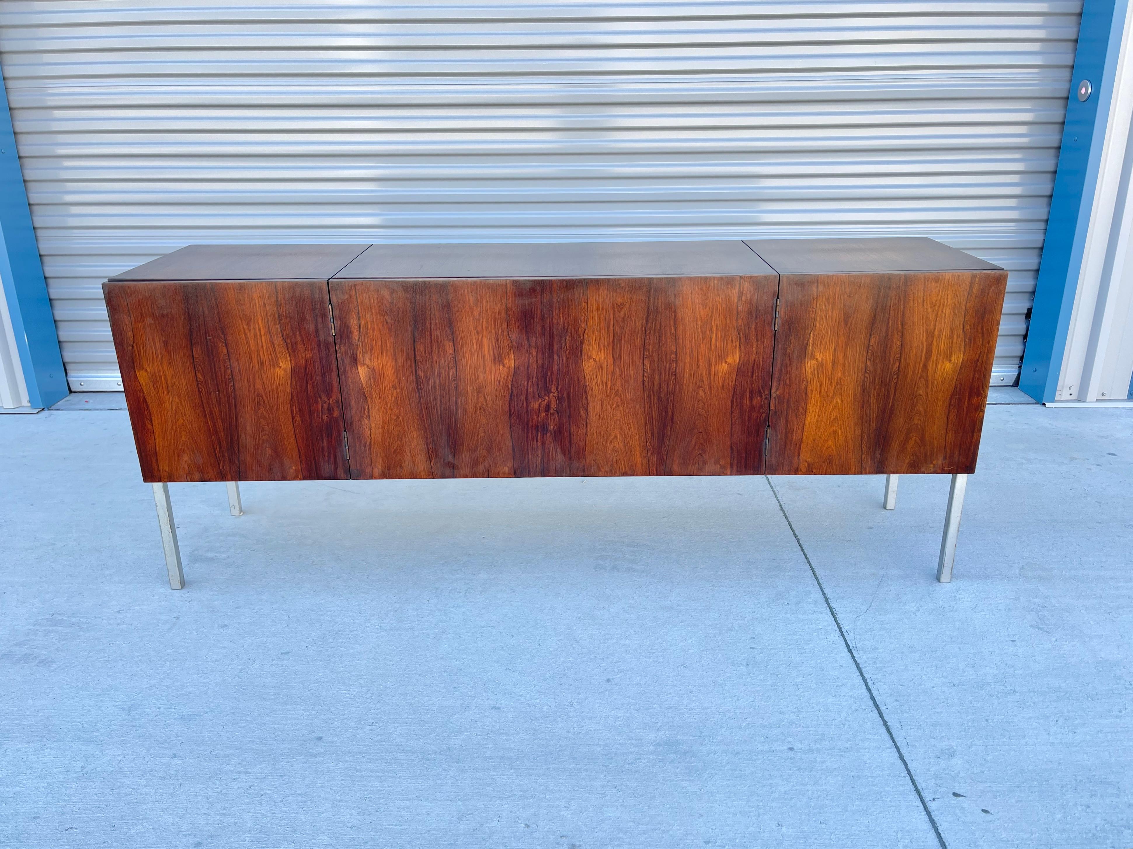Mid-century rosewood credenza was designed and manufactured in the United States circa 1960s. This beautiful cabin features two pull-out doors and a secret compartment on the top, a rosewood frame that gives an excellent color tone, and a beautiful
