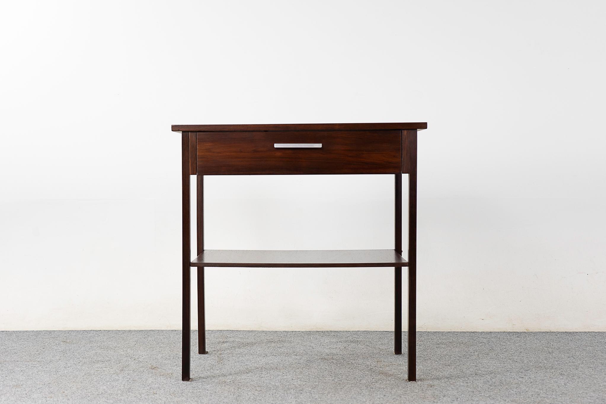 Rosewood mid-century side table, circa 1960's. Solid wood construction on the base and handsome book-matched veneer on the flat surfaces. Sleek drawer and lower shelf, pop this by your front door!

Please inquire for remote and international