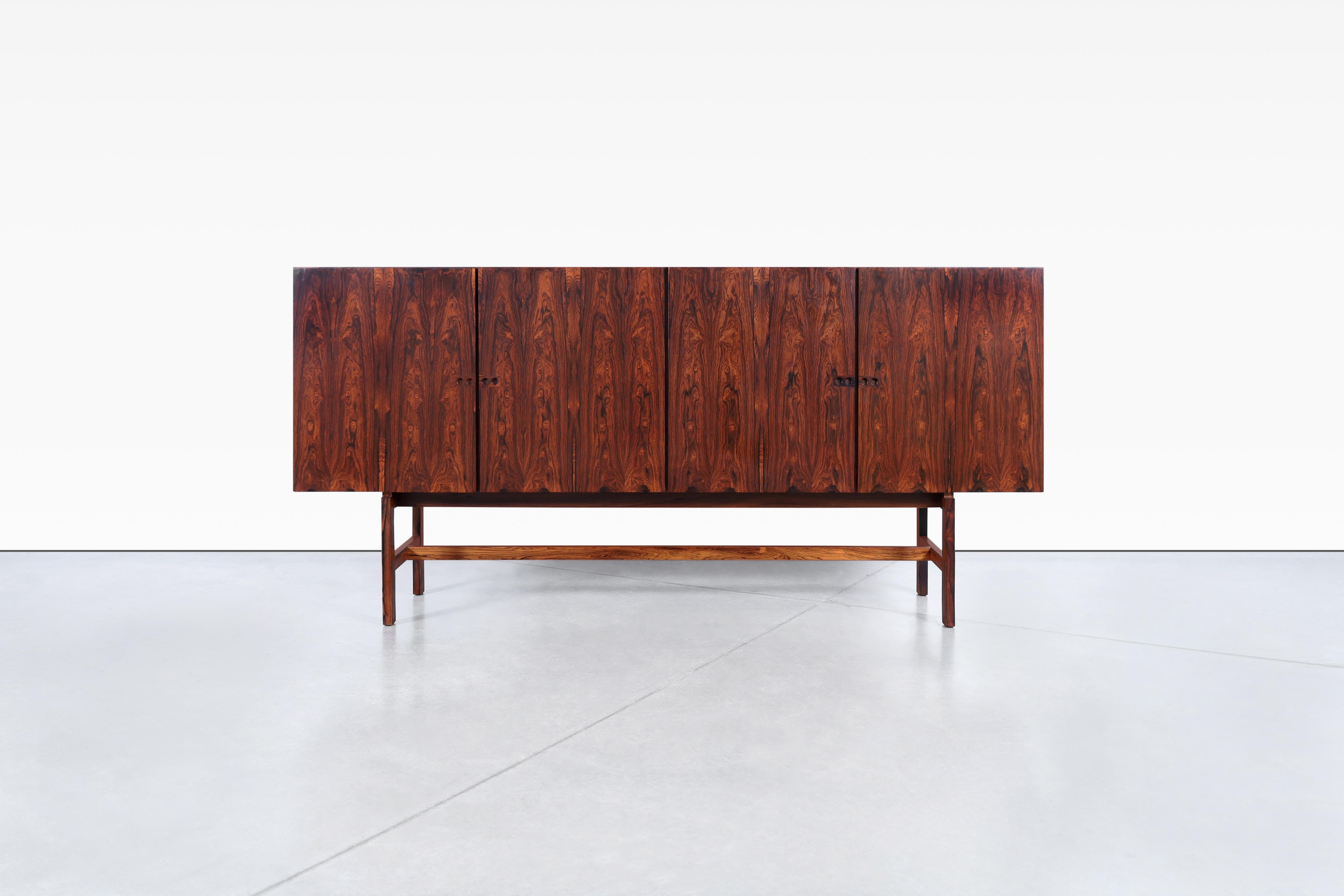 Behold the exquisite Danish modern rosewood sideboard attributed to Ib Kofod Larsen, originating from Denmark in the 1960s. This rare gem boasts the use of Brazilian rosewood, a coveted material in today's market. The piece showcases four