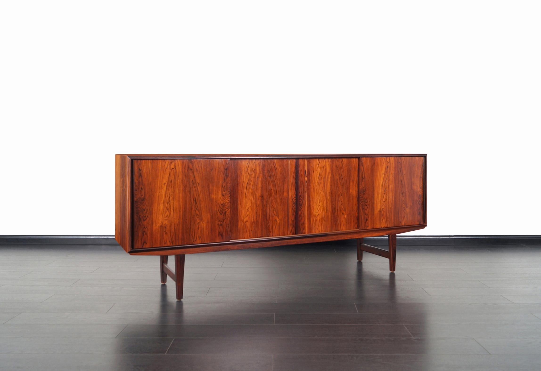 Danish modern rosewood sideboard designed by E.W. Bach for Sejling Skabe in Denmark, circa 1960s. Features four sliding doors that opens up to three sections. The middle section reveals a large adjustable shelf. The sections on each end contains an