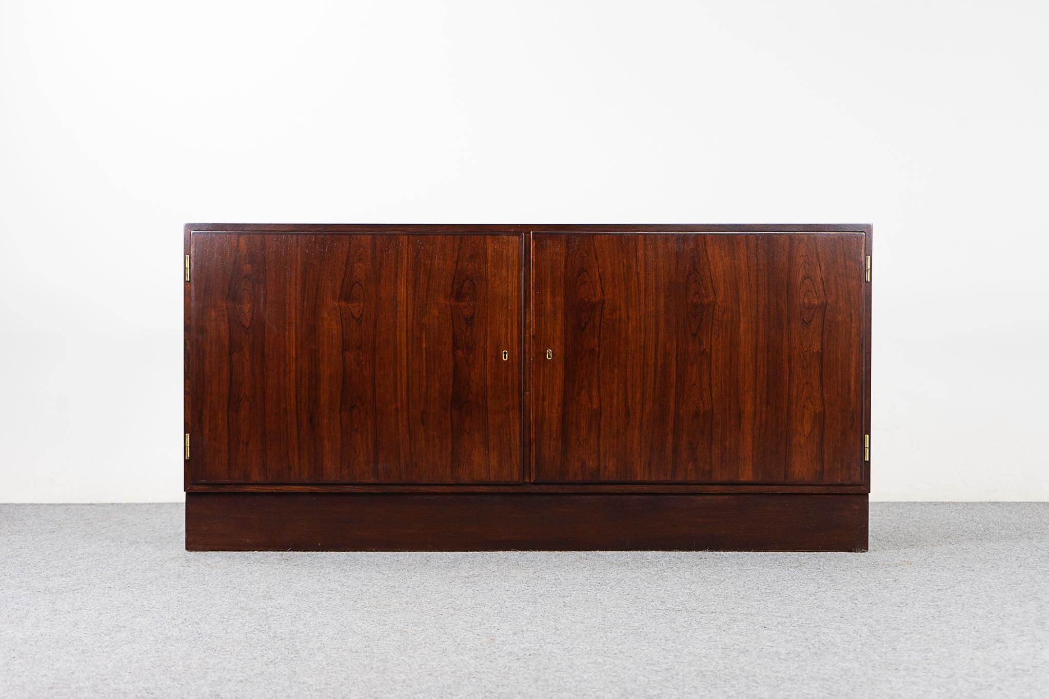 Rosewood midcentury sideboard by Hundevad, circa 1960s. Clean, simple lined design and exceptional book-matched veneer throughout. 2 Adjustable shelves on one side, open cubby on the other. Danish Furniture Makers' Control stamp intact.

Please