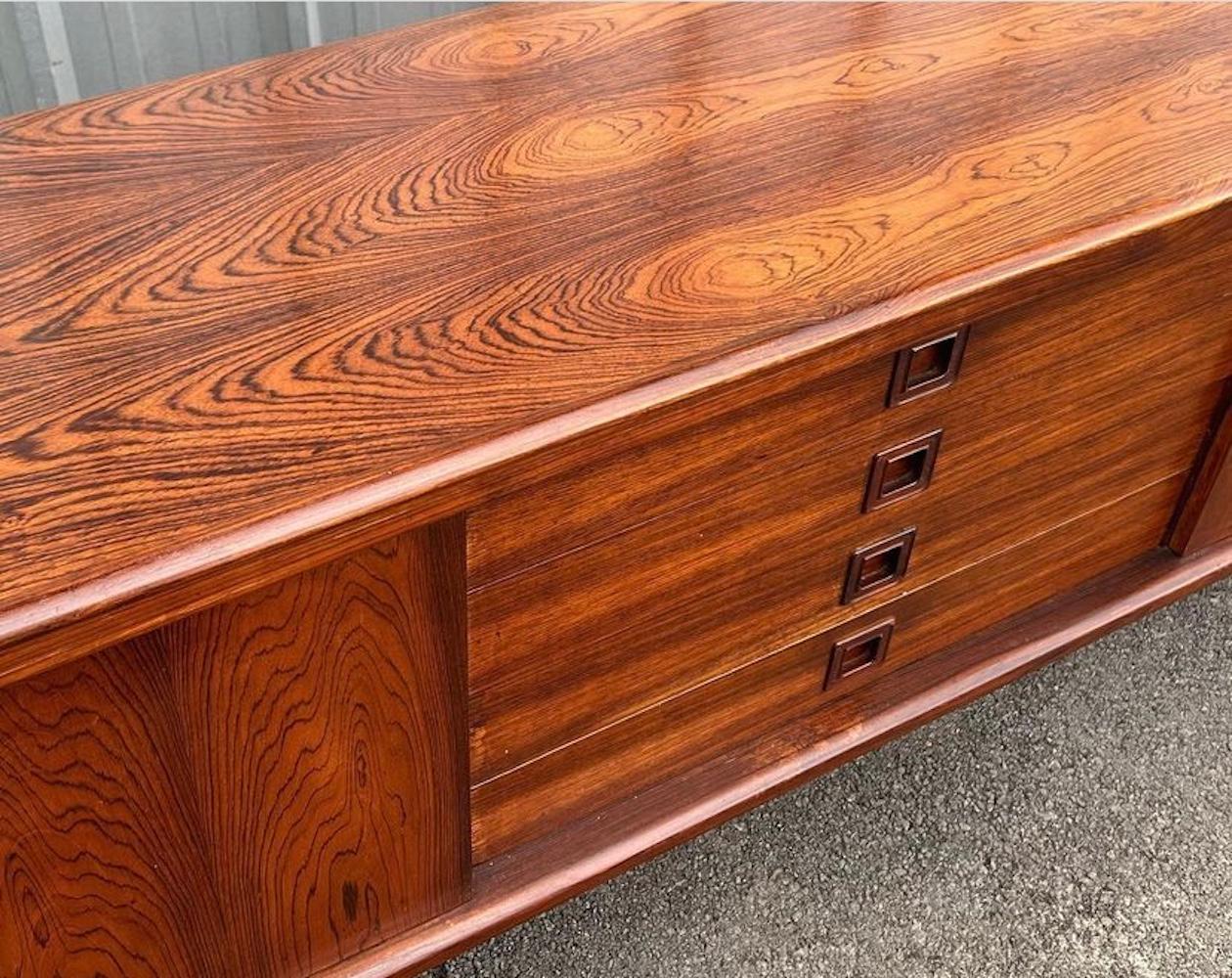 Danish Modern Rosewood sideboard by HW Klein for Bramin features a finished back, four drawers with uniquely sculpted pulls, and two sliding doors that open up to spacious shelving (a total of 4 shelves). This vintage sideboard measures at 88.50