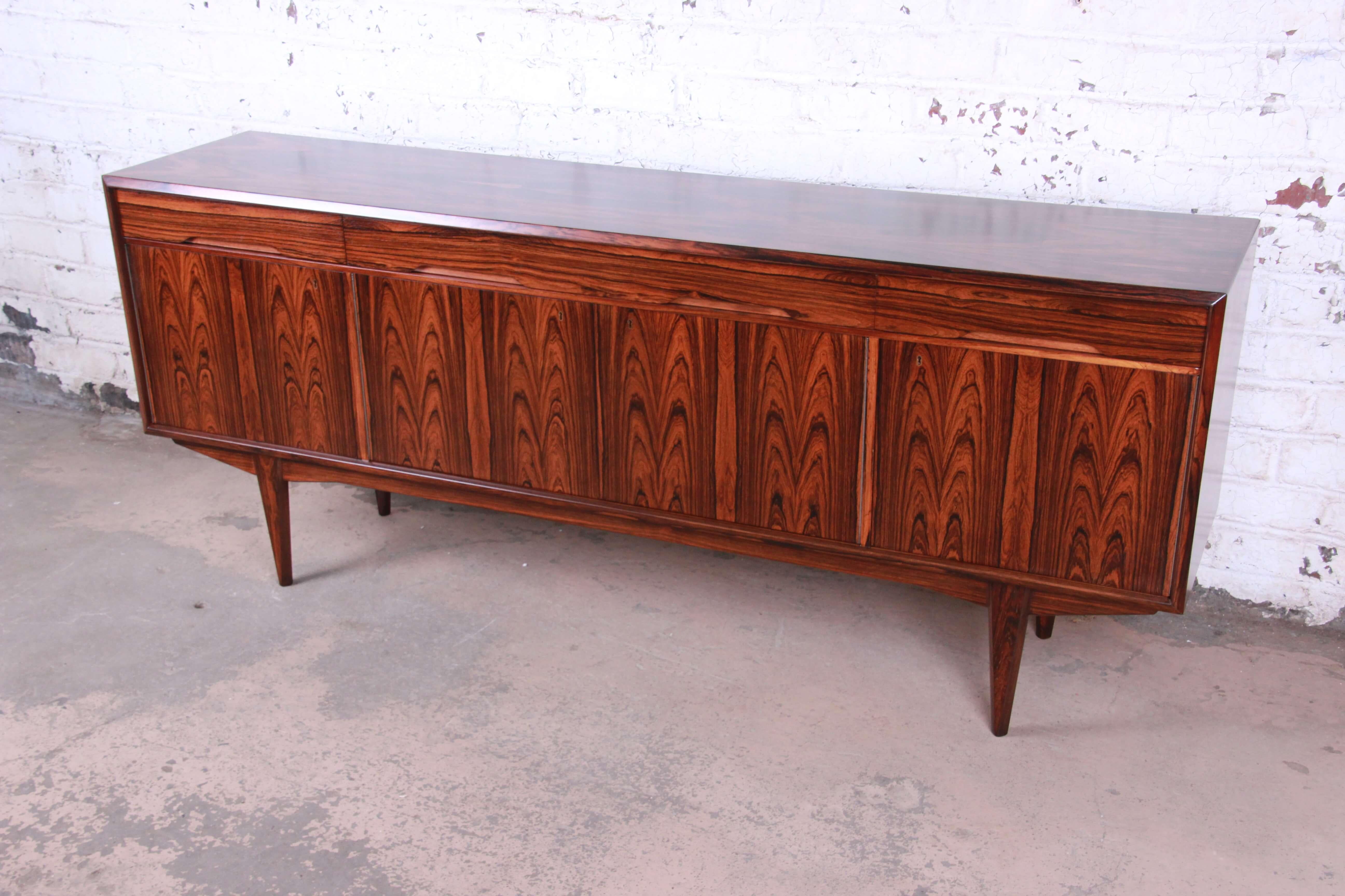 Offering an exceptional rosewood Danish modern sideboard credenza. This Scandinavian piece has fantastic wood grain and is also finish on the back. There are two smaller drawers on each end of the top and a larger drawer in the middle. Below is a