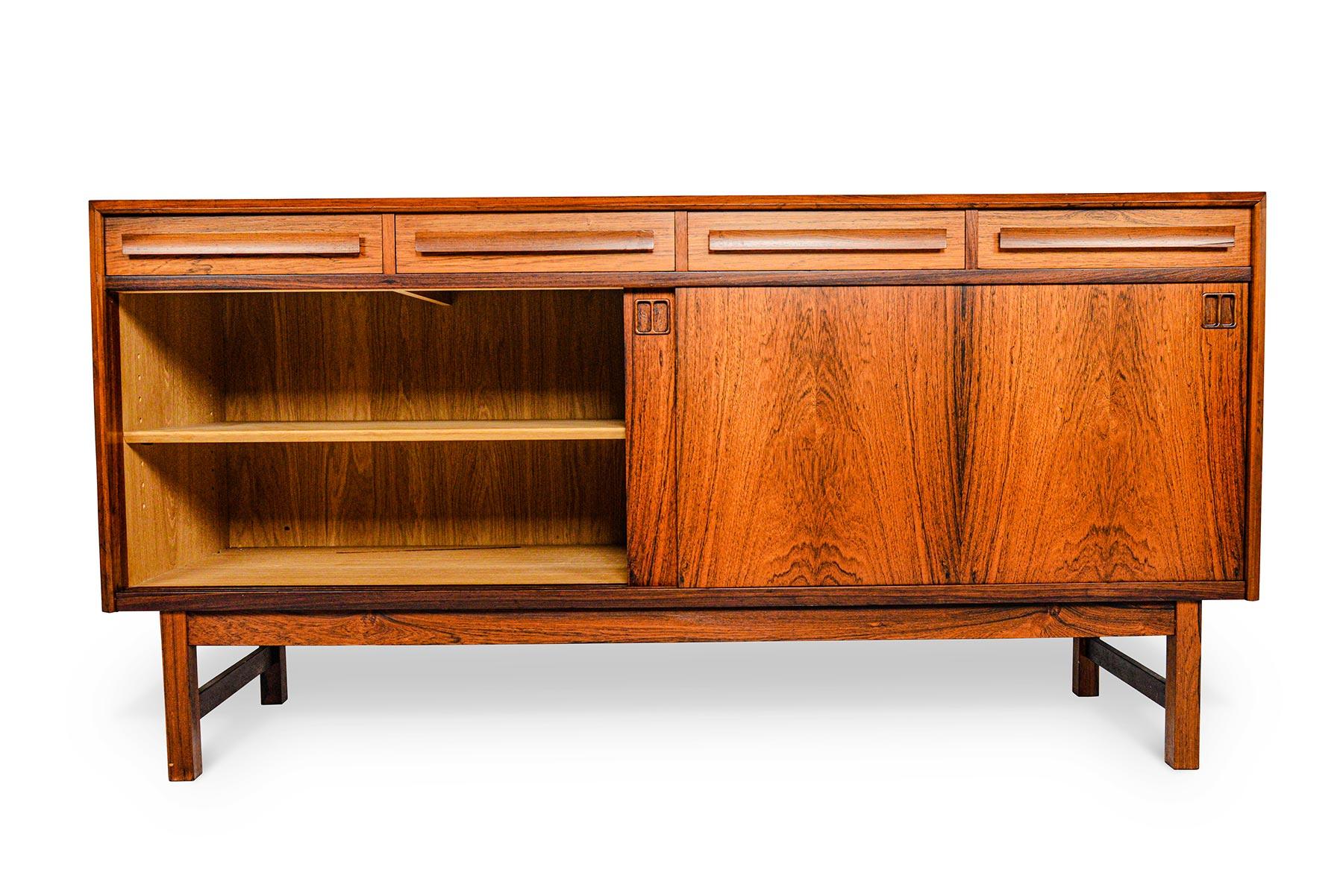 This mid-sized Danish modern midcentury credenza is crafted in rosewood and offers exceptional storage capabilities! With bold, modern lines, this piece can easily slip into any decor. Two large sliding doors open to reveal two bays outfitted with