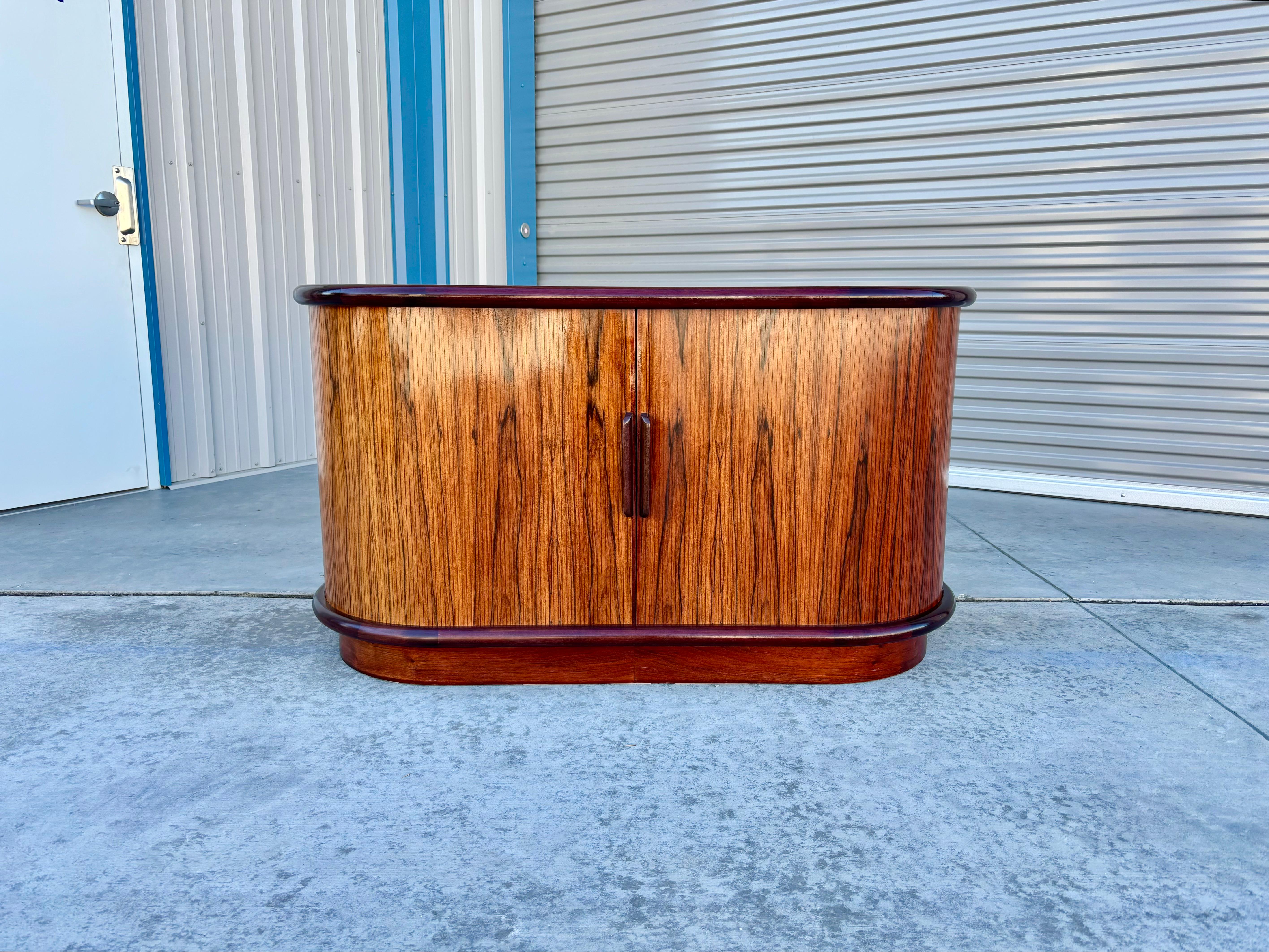 Danish modern rosewood cabinet designed and manufactured in Denmark circa 1960s. The warm and richly-hued rosewood frame is complemented by a unique tambour door front that adds visual interest and texture. Once opened, this cabinet reveals ample