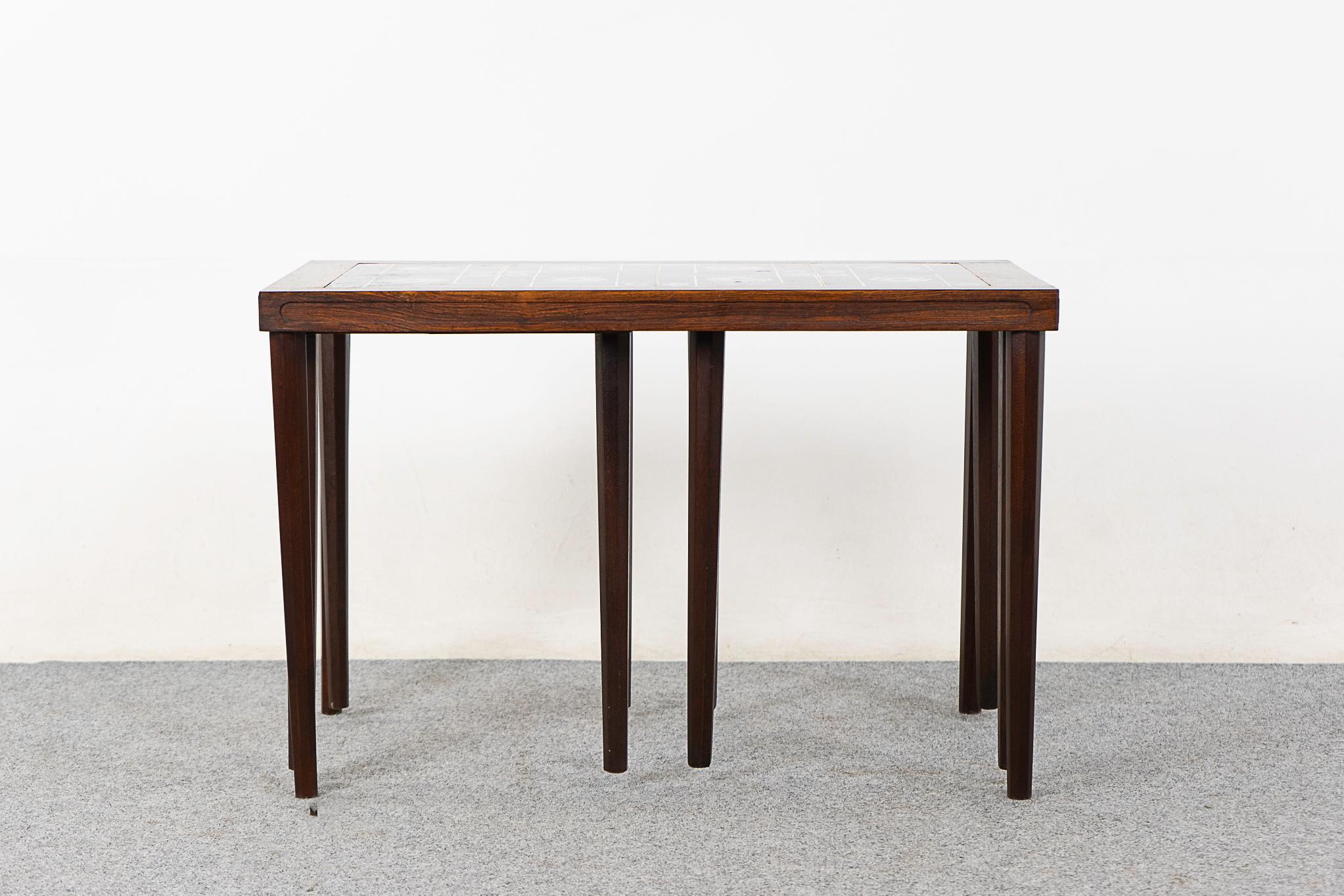 Rosewood and tile mid-century nesting tables, circa 1960's. Space saving design, the footprint of one table with the functionality of three! The geometric/floral motif contrasts beautifully with the warm tone of the rosewood.

Unrestored item, some