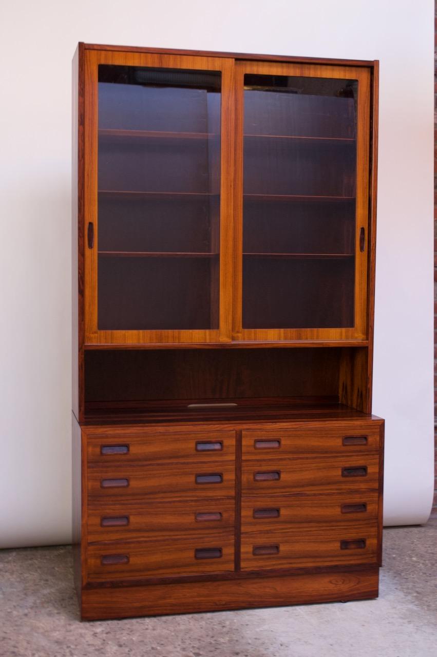 Danish rosewood two-piece hutch / bookcase manufactured in the 1960s by Poul Hundevad. The top display unit / vitrine is supported by an eight-drawer chest all exhibiting exquisite bookmatched veneer, expertly refinished. 
The vitrine top features