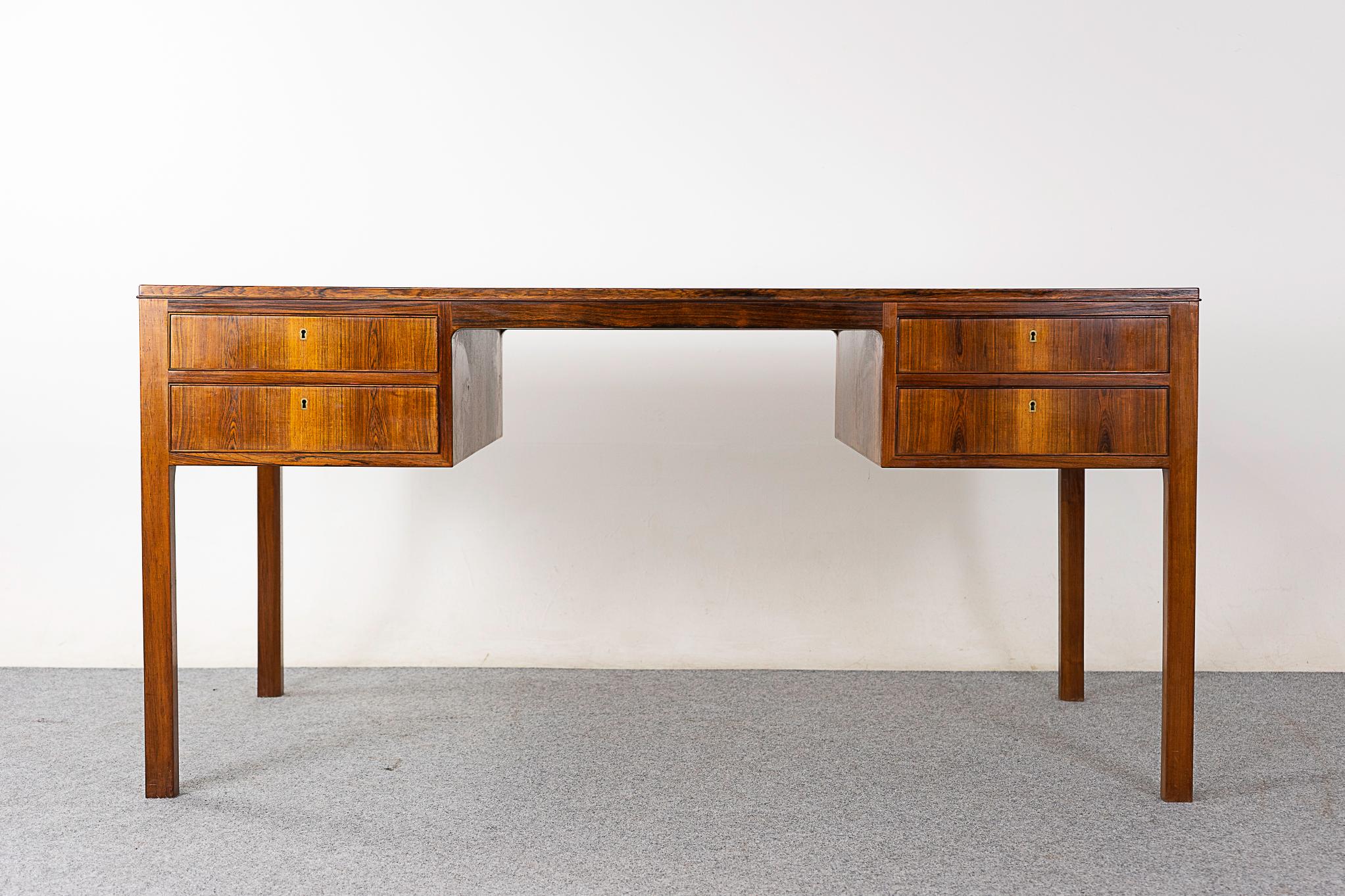 Rosewood mid-century desk, circa 1960's. Sleek uncluttered design with bookmatched veneer top. Four locking drawers with beautiful grain match up!  