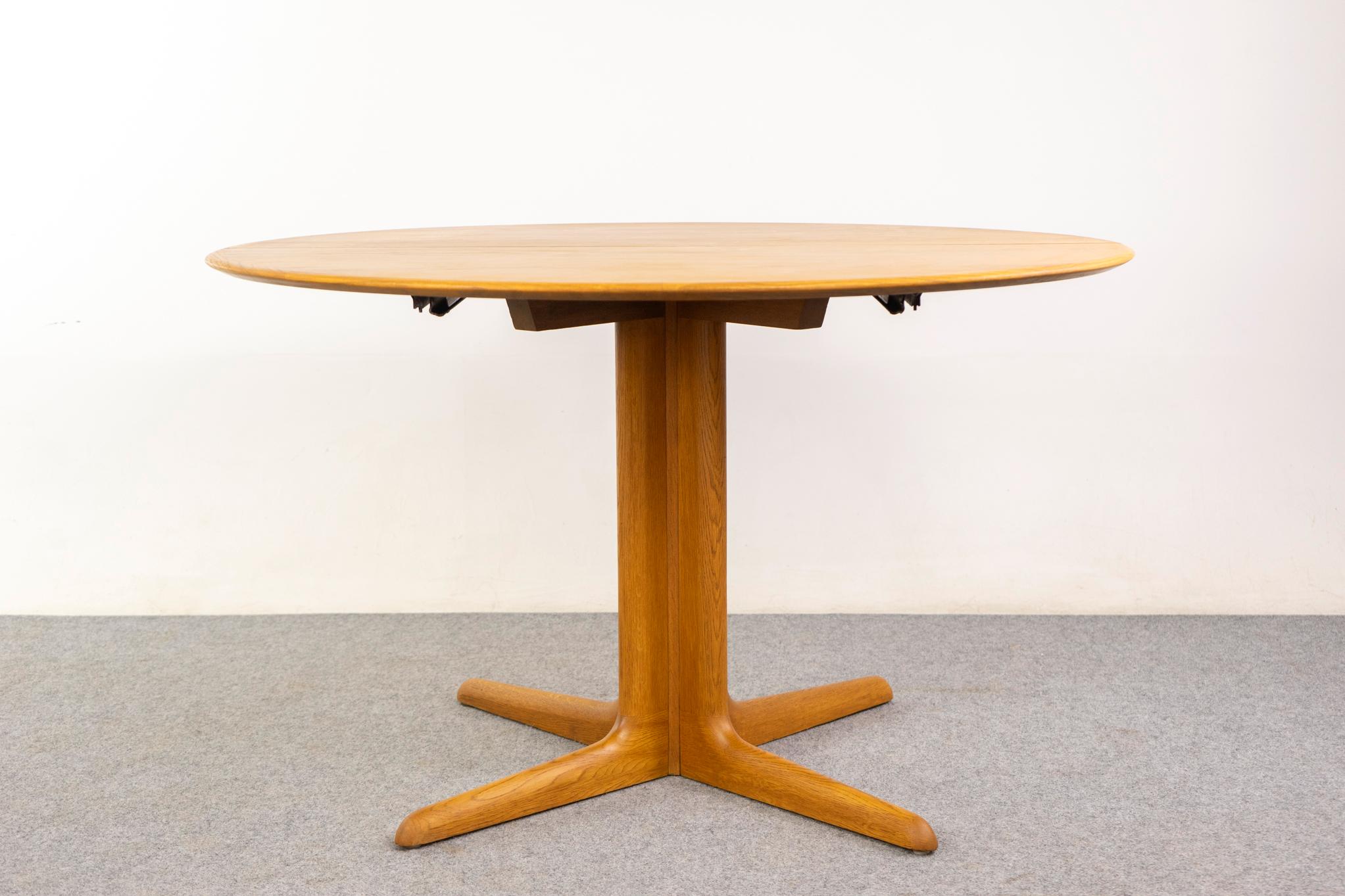 Oak Danish dining table, circa 1960s. Circular top rests on sculpted pedestal base. Add leaves as needed; the base splits to support the extra weight.

Made in Denmark
Circa 1960's
47