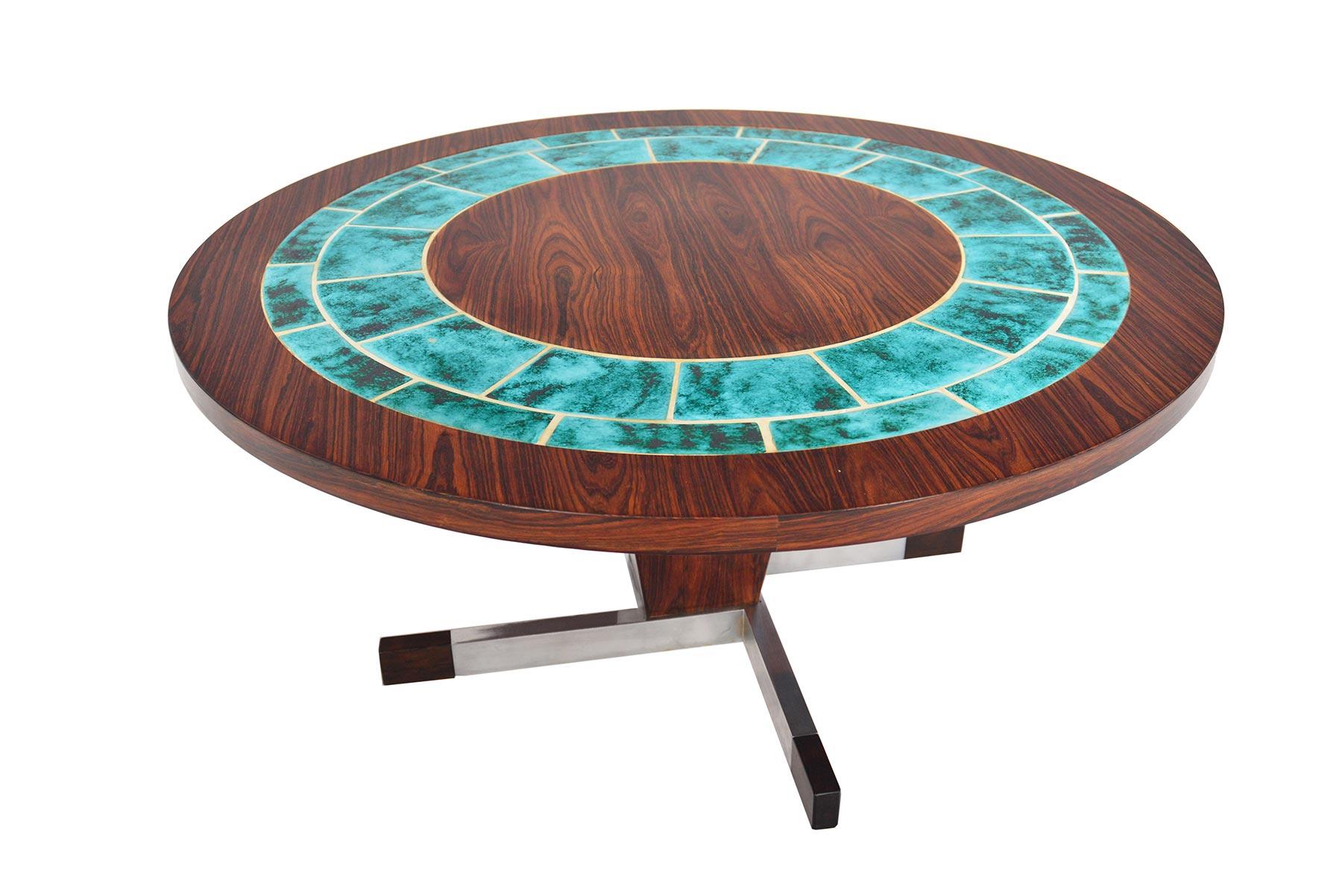 This round Danish modern rosewood coffee table offers eye-catching style and design details. The round rosewood top is inlaid with turquoise ceramic tiles and stands on a rosewood and steel base capped in rosewood. In excellent original