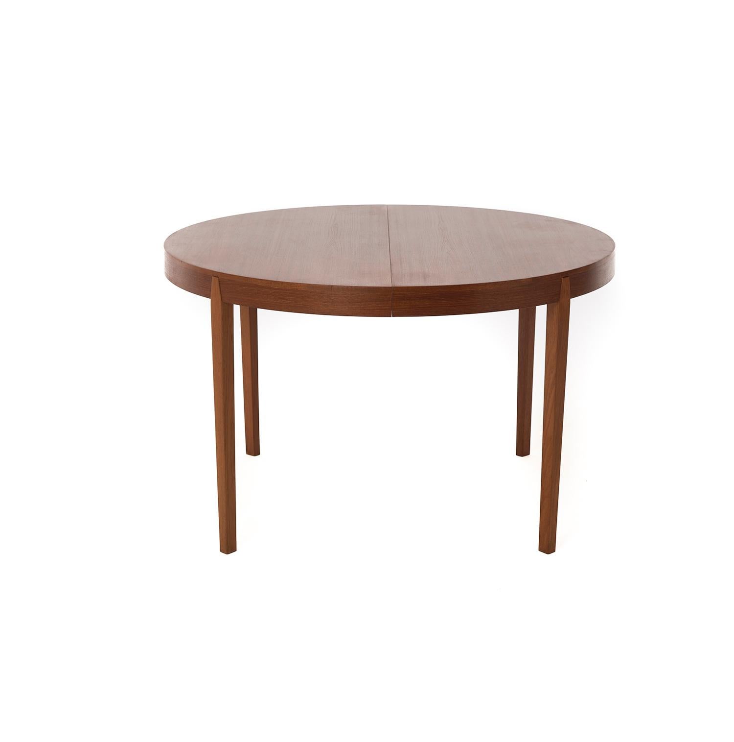 This Danish modern teak dining table is round at it's smallest and becomes an oval with the insertion of one or two aproned leaves. Leg detail sets into apron in a pleasing way. Oiled old growth teak. Seats 10-12.