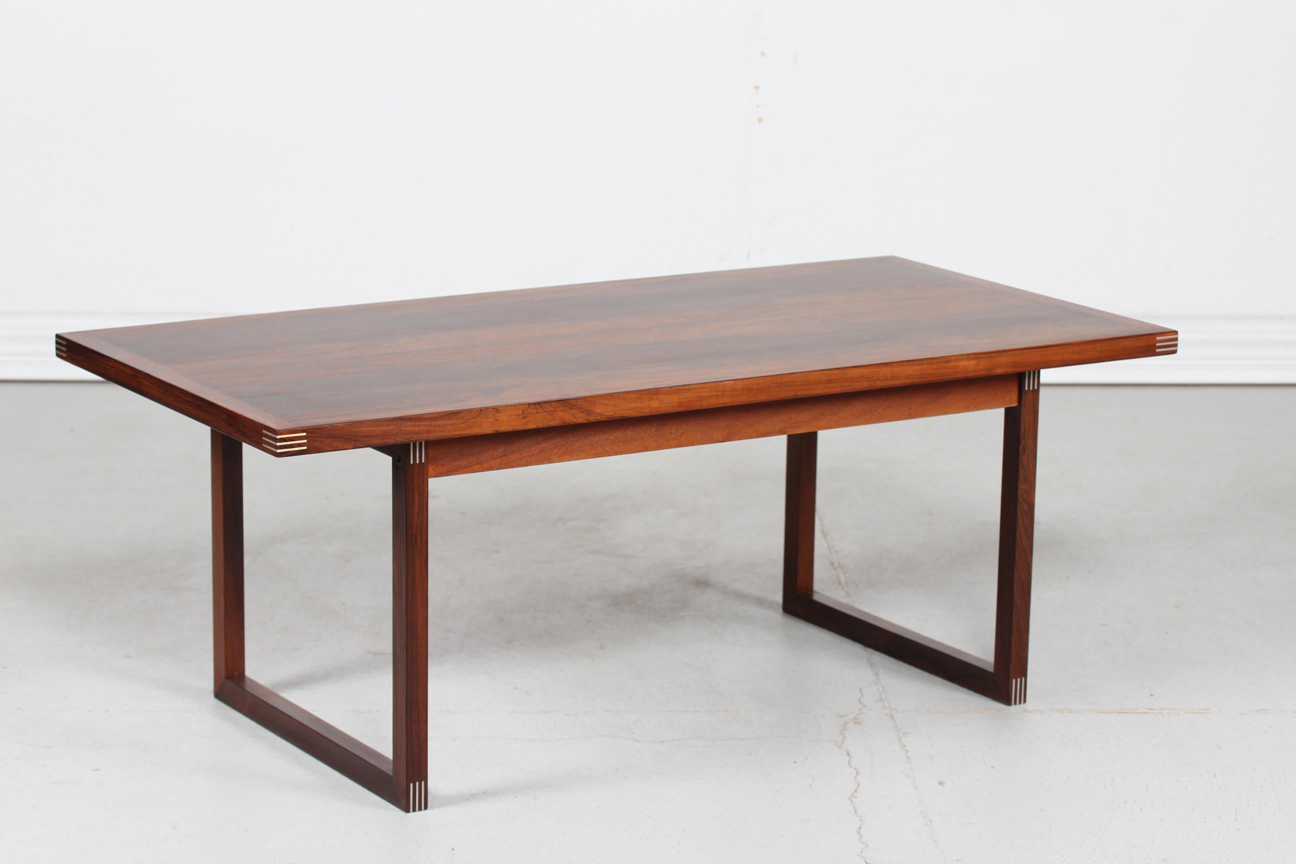 Danish modern sleight leg coffee table made of rosewood.
Created by furniture designer Rud Thygesen (1932-) and manufactured by Heltborg Møbler in Denmark 1970s 

The table is made of rosewood with inlaid aluminium and remains in very nice