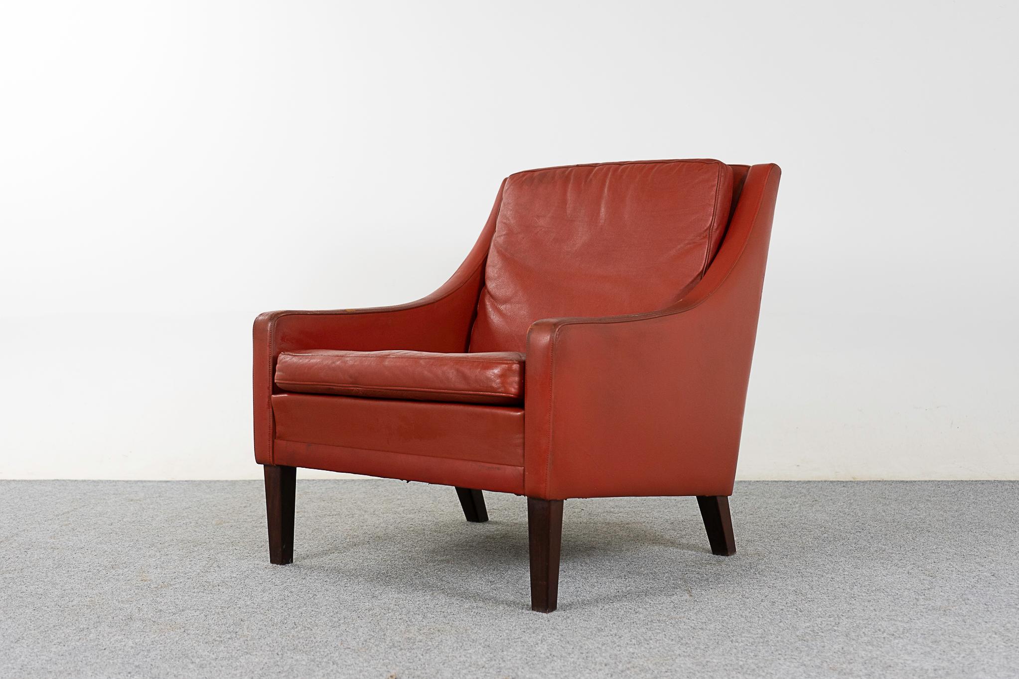 Leather mid-century lounge chair, circa 1960's. Swooping arms and robust angled legs. Original rust colored leather in nice condition, some marks consistent with age on the hand rests. Comfortable!

Please inquire for remote and international