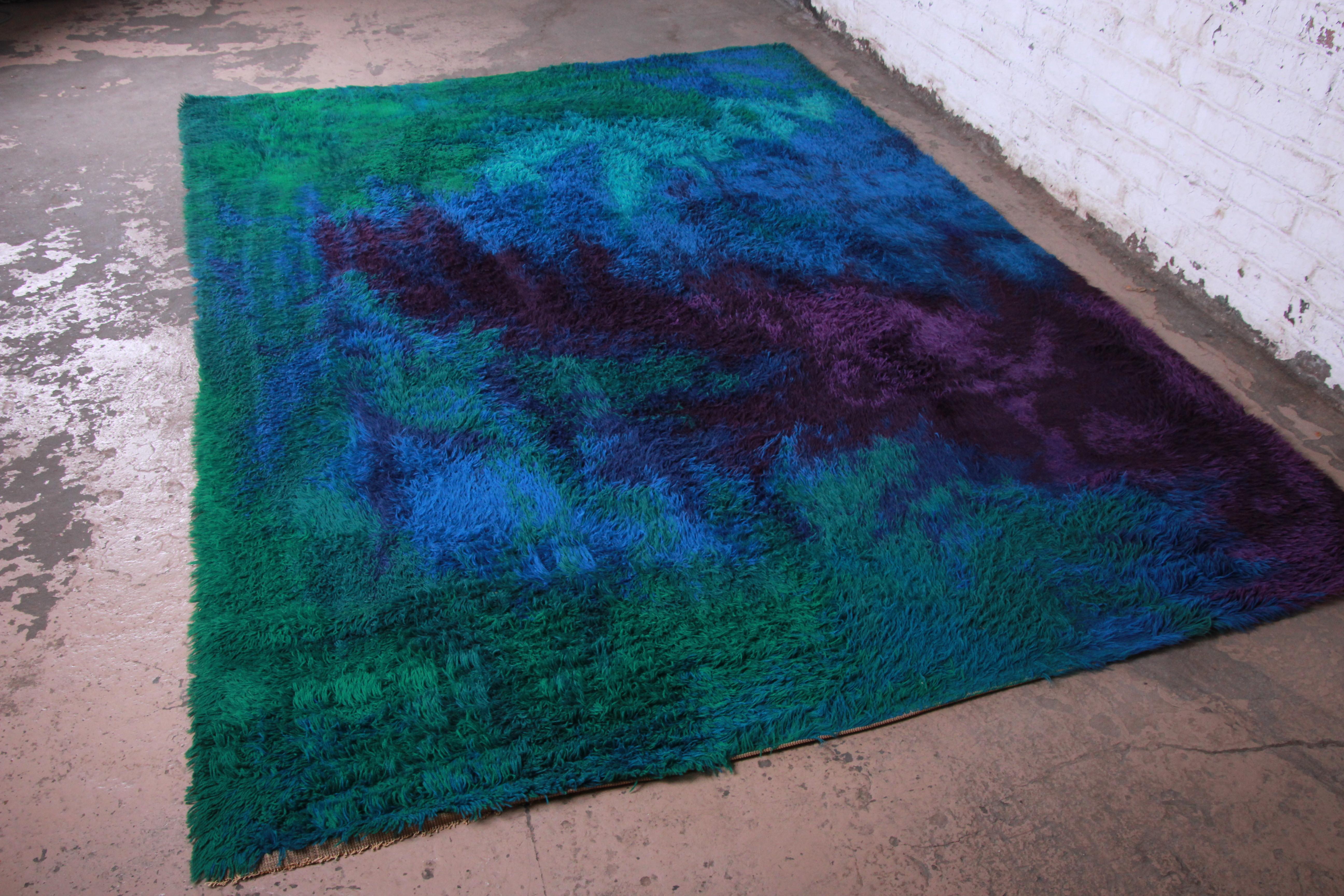 A stunning midcentury Danish Modern rya shag rug. The rug has a unique abstract design in very vivid colors of purple, blue, teal and green. It has a thick, soft wool pile, with just a couple areas of low pile as pictured. A very nice and clean rug