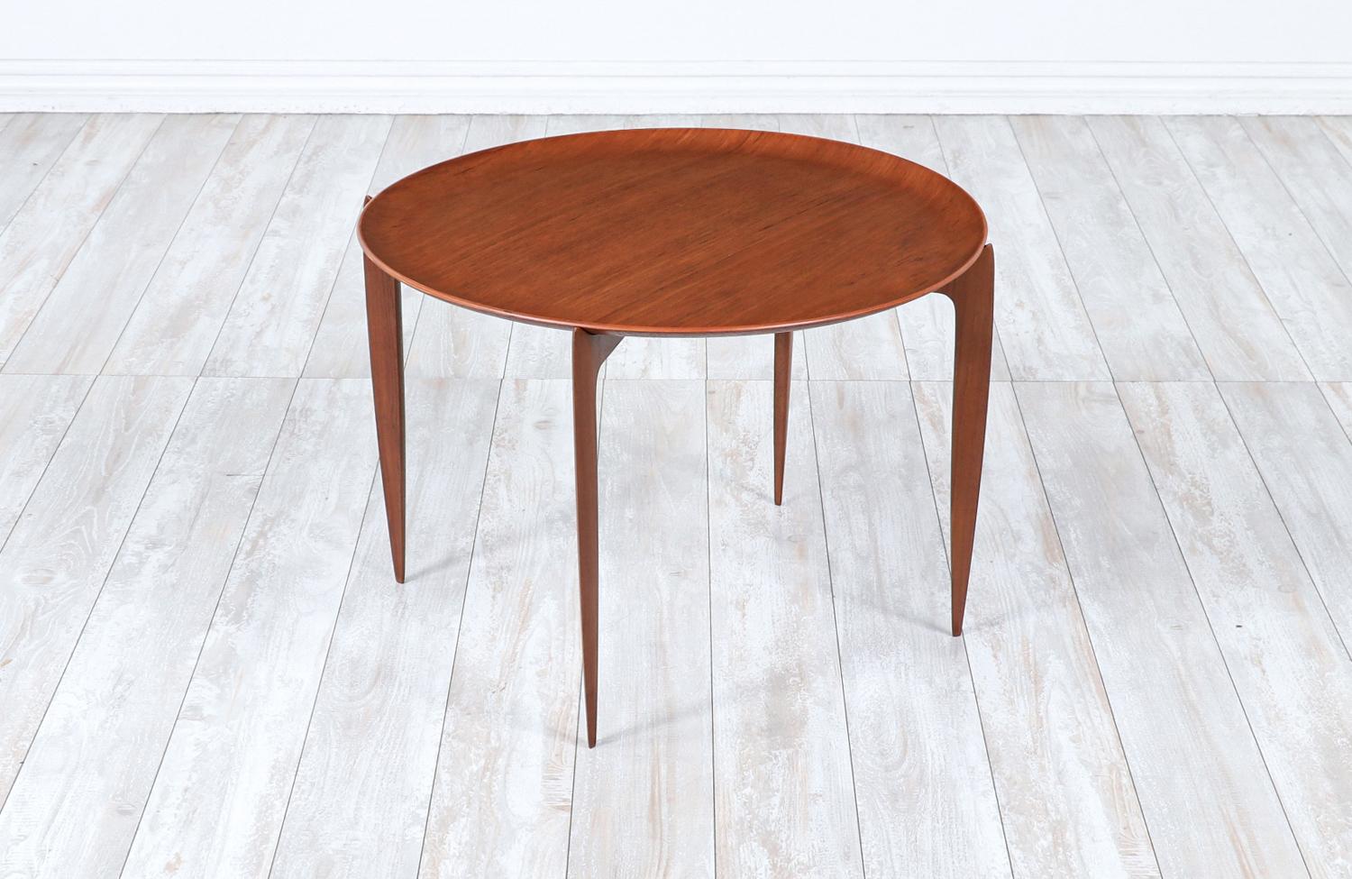 Versatile Danish Modern tray table designed by H. Engholm & Svend Åge Willumsen for Fritz Hansen in Denmark circa 1950s. This extraordinary and practical table design features a sculpted teak wood base with a spider leg base and a rounded teak tray