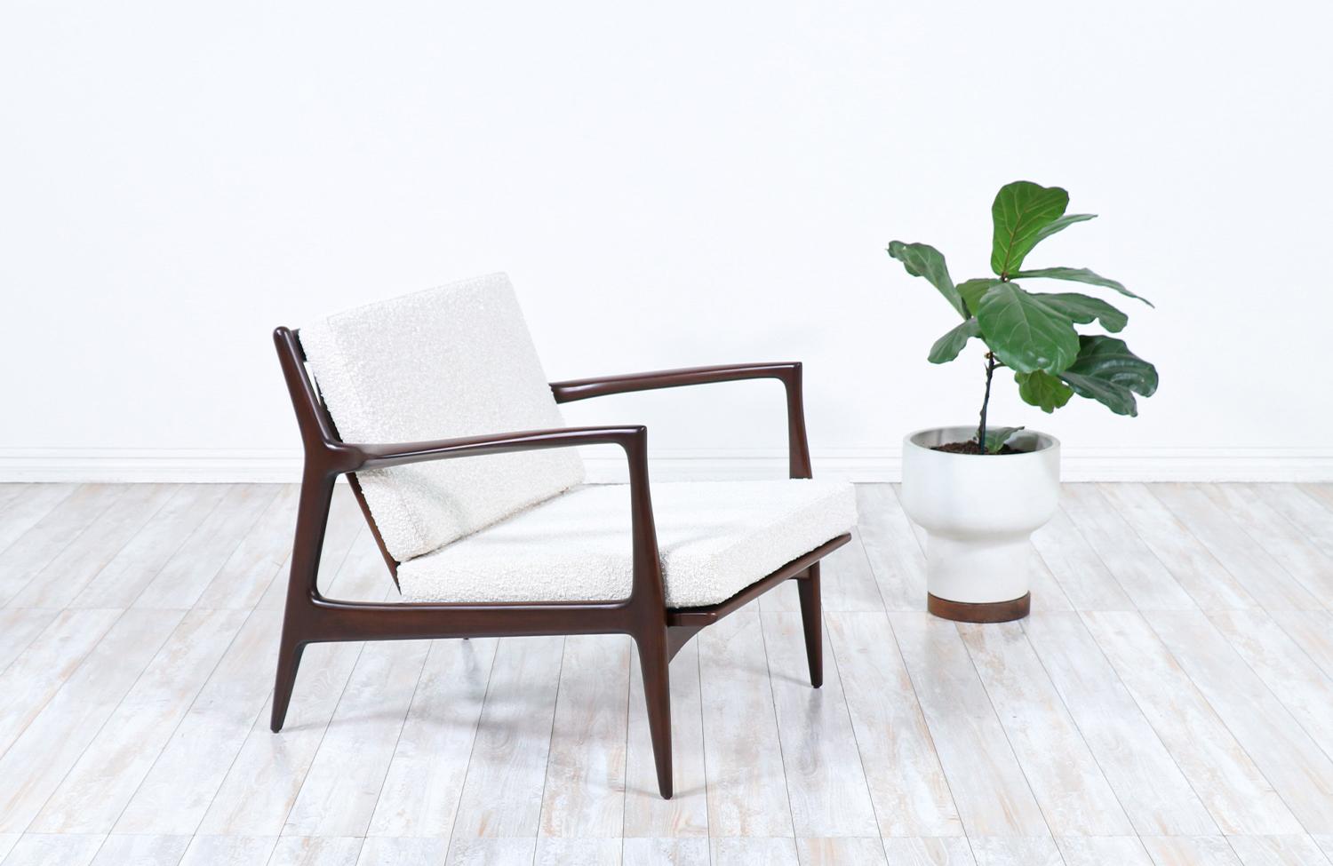 Stylish lounge chair designed by Ib Kofod-Larsen for Selig in Denmark circa 1960s. This sleek and ergonomic lounge chair features a sturdy wood frame with angled legs and a sculptural slatted back that is held in place by a bowed perpendicular