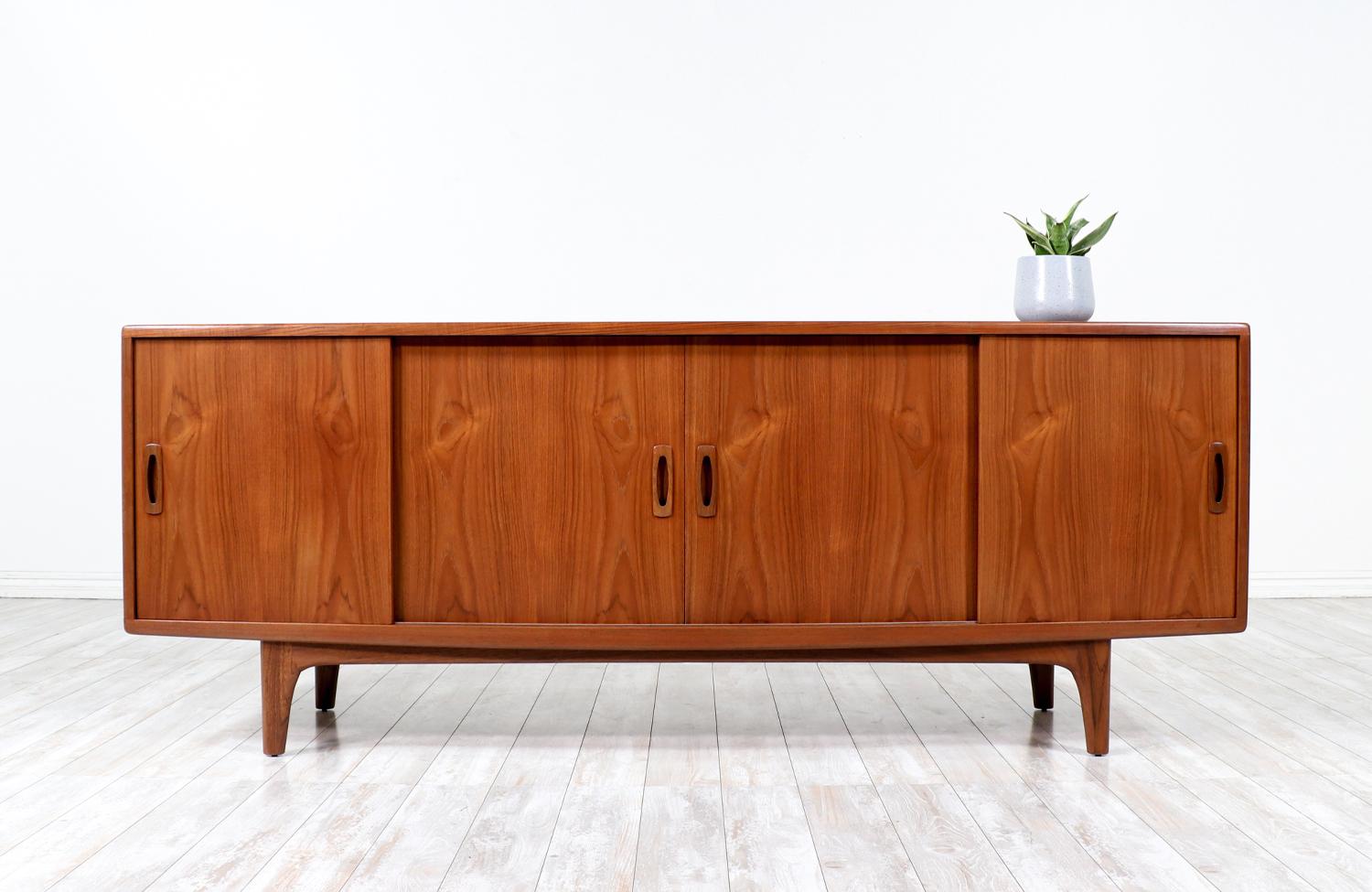 Stunning credenza manufactured circa 1960’s. This credenza features an elegant teak wood case with with ample storage. The four sliding doors give great functionality for easy open, sculpted teak pulls and panels of magnificent grain details.  The