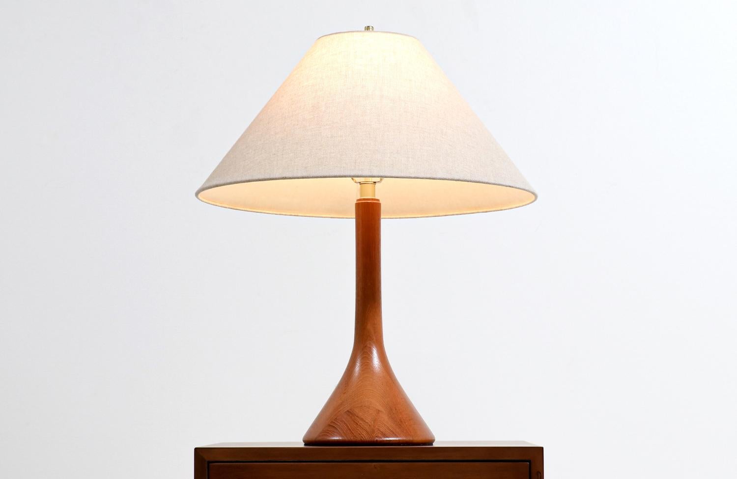Danish modern sculpted teak table lamp.

Dimensions
27in H x 8in W x 8in D 
Lamp Shade: 11in H x 22in W.
 