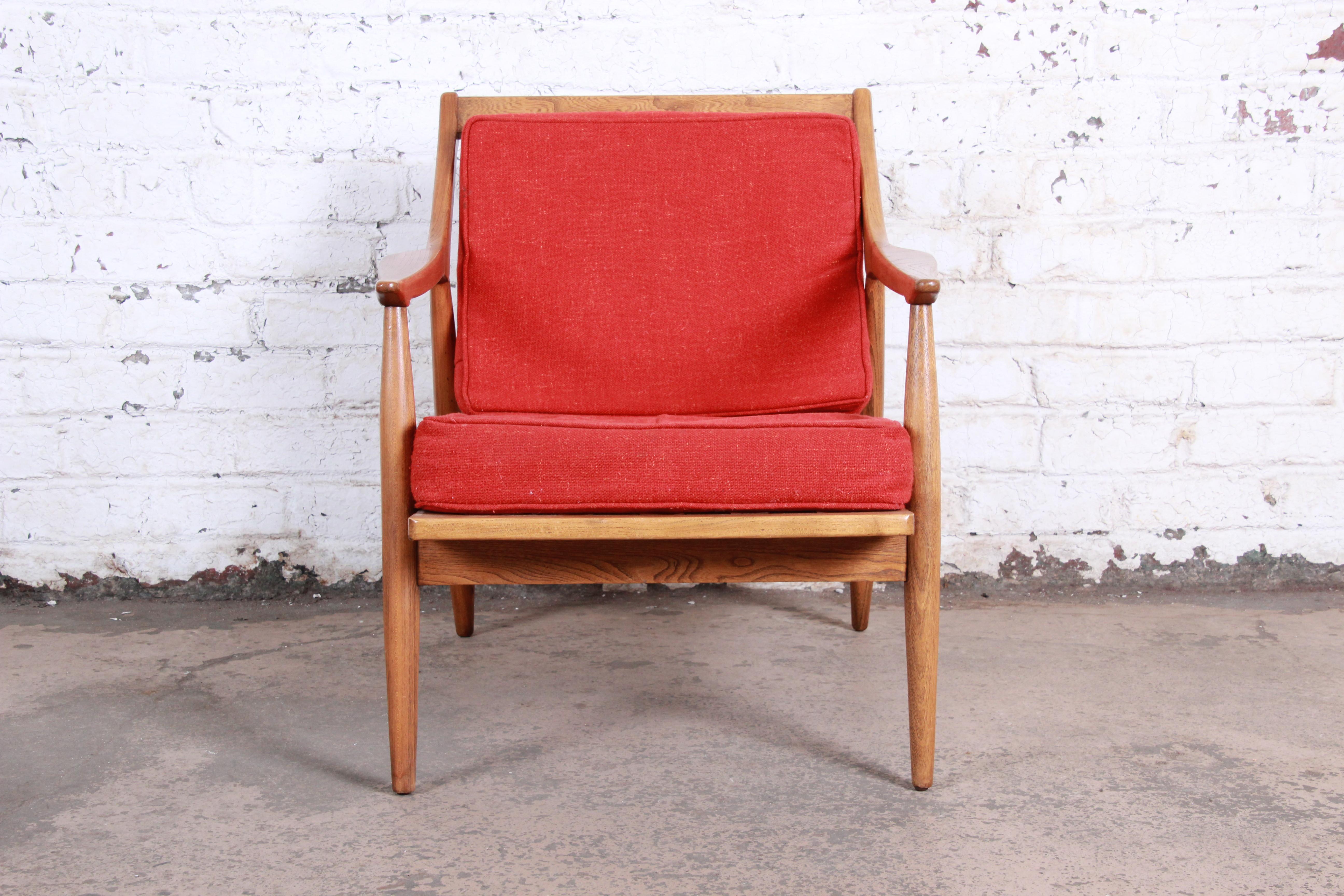 A gorgeous midcentury Danish modern sculpted walnut lounge chair. The chair features a sleek sculpted solid walnut frame with seat and back cushions in original red upholstery. Marked 