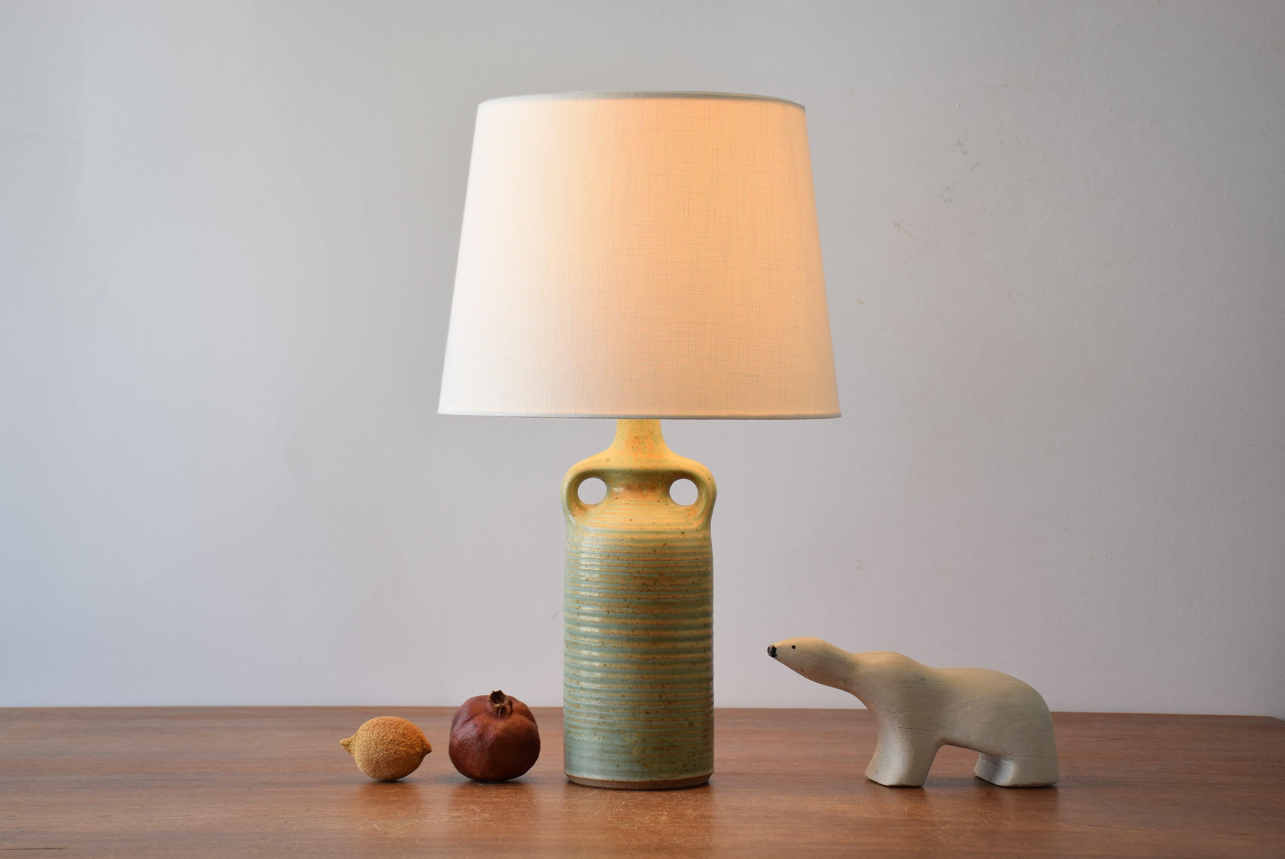 Stylish mid-century Danish table lamp from the ceramic workshop Knabstrup. Designed and made ca 1960s or 1970s.
The lampbase is made of stoneware and has a matte pale green glaze with ochre golden elements. It has a structured striped