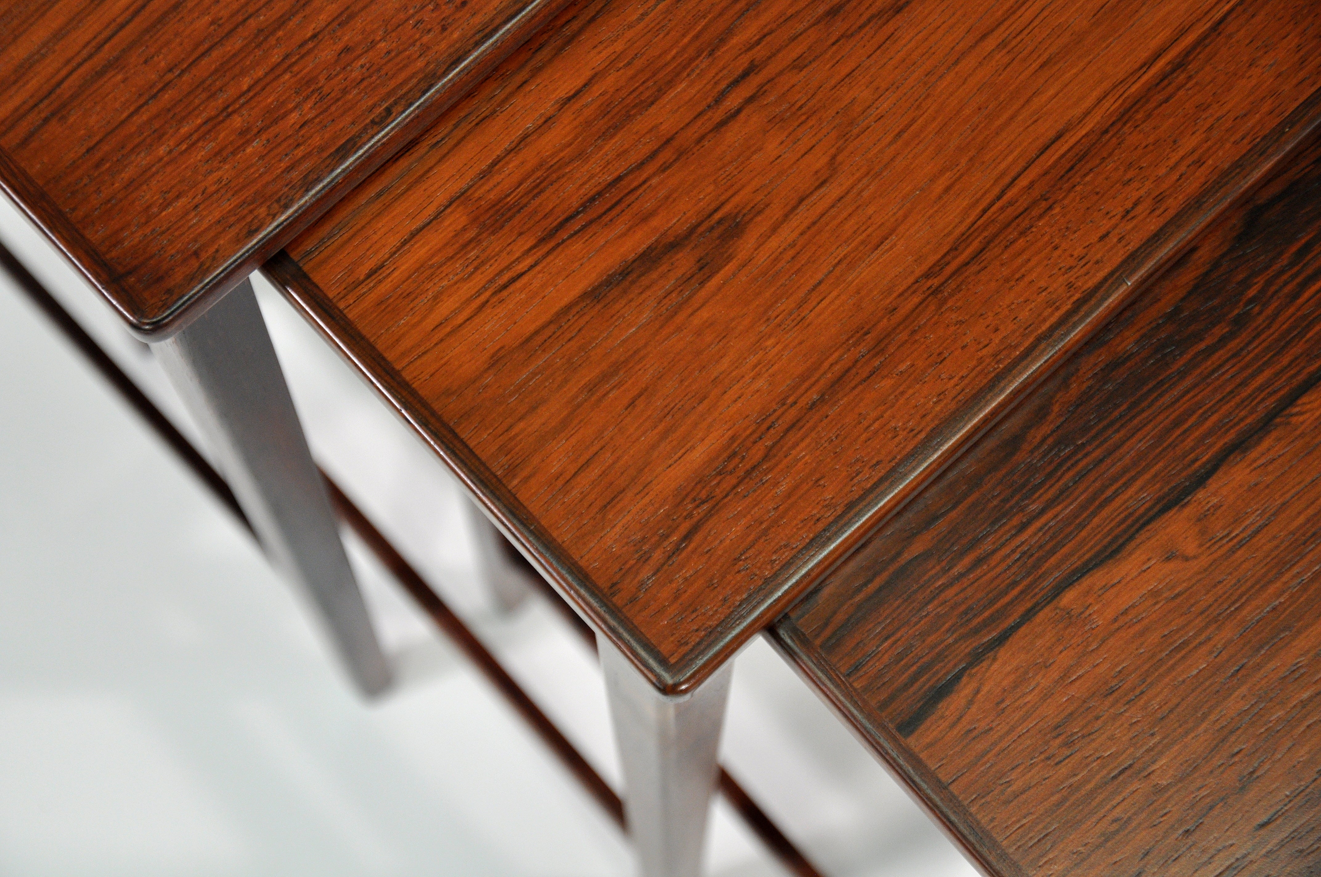 Un ensemble vintage de trois tables empilables en palissandre brésilien du milieu du siècle, en parfait état. Ce nid de 3 tables modernes scandinaves présente des motifs de grain étonnants et des lignes épurées. Les plateaux ont des coins légèrement