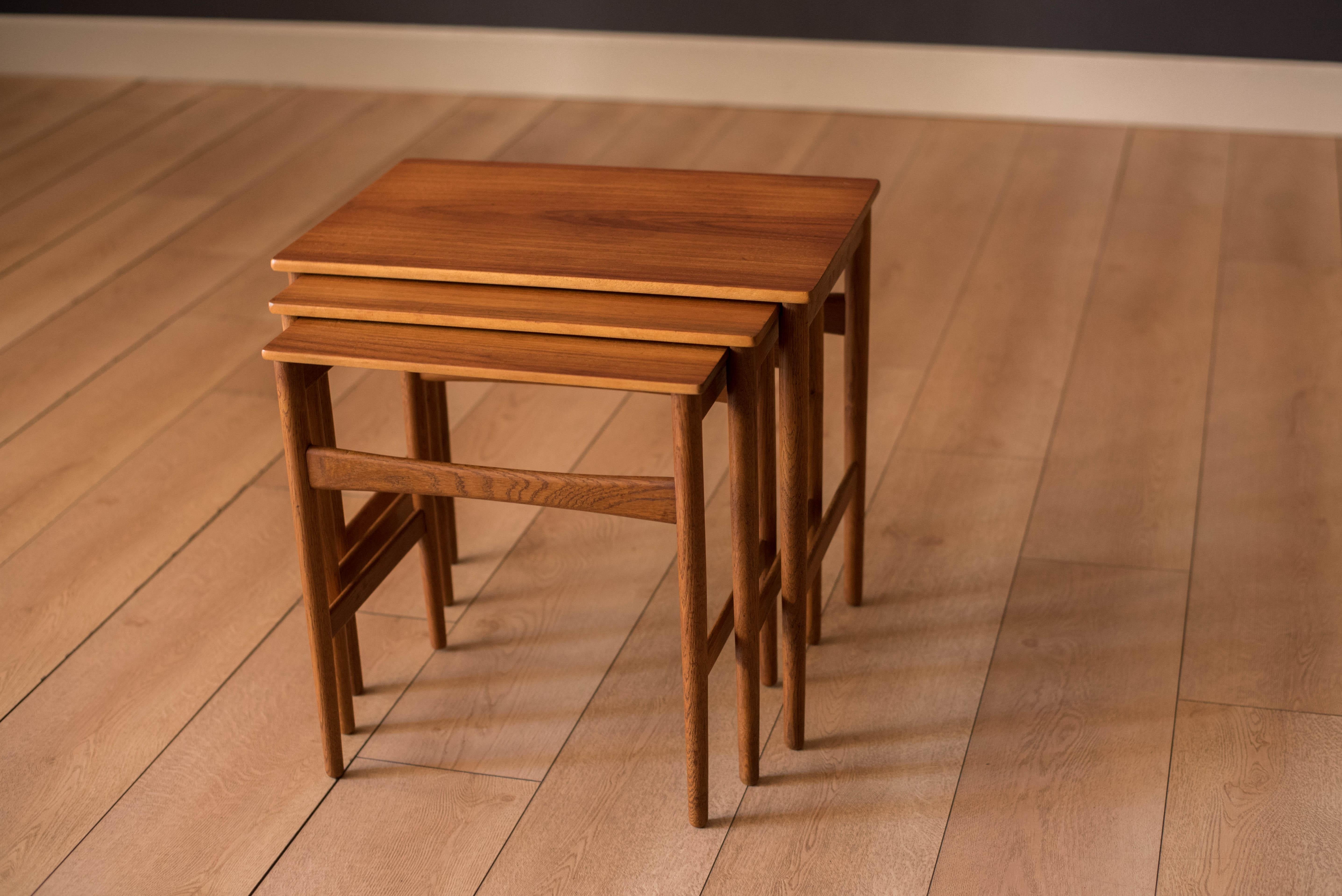 Mid-Century Modern set of three nesting tables in teak designed by Hans Wegner for Andreas Tuck, Denmark circa 1960's. This set features contrasting beech edge banding and supporting oak legs. Includes three separate end tables in various sizes that