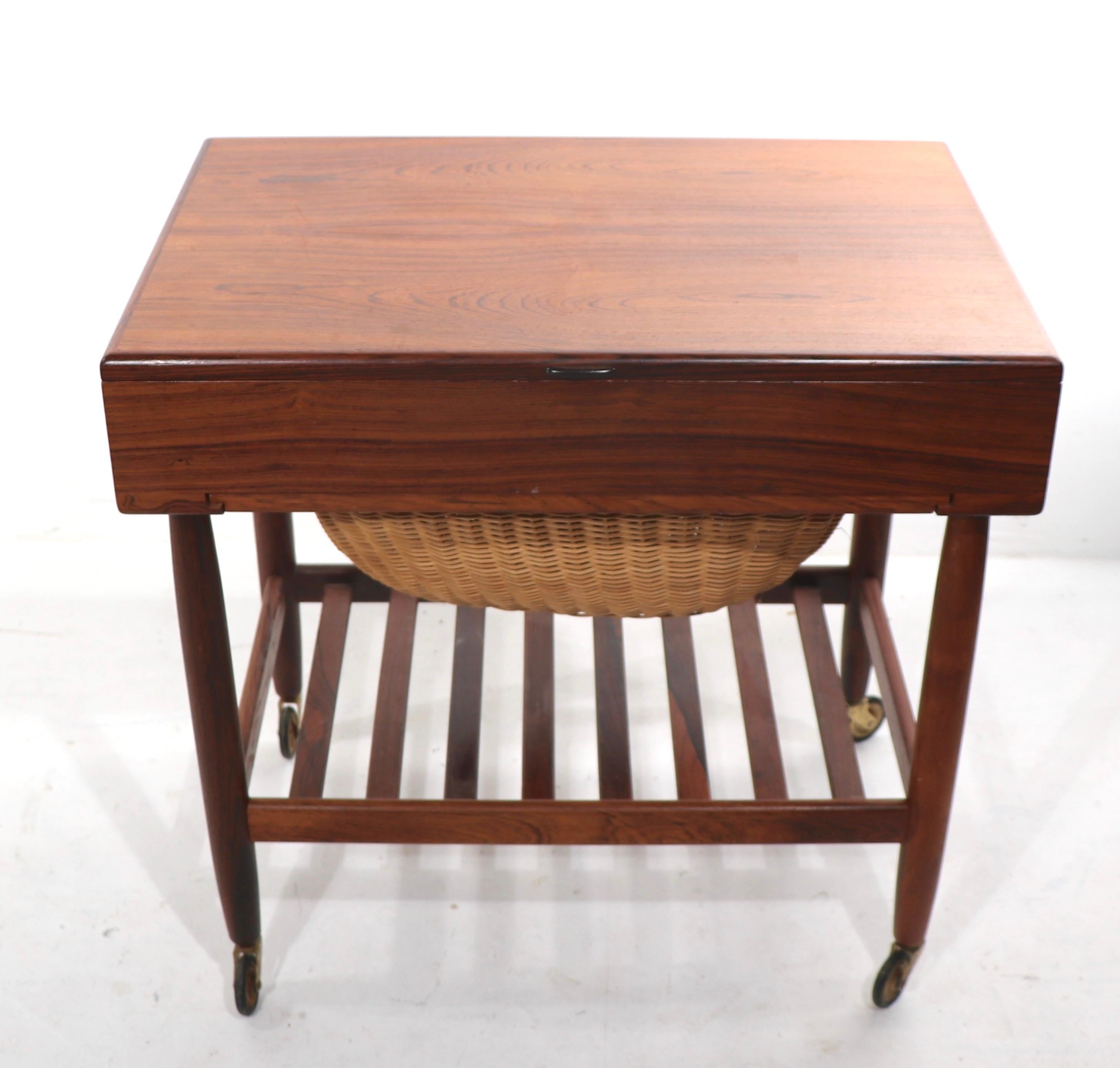Exceptional Danish design sewing cart, designed by Ejvind Johansson made in Denmark by FDB Mobler. The exterior is in stunning rosewood, and rosewood veneer, while the interior is in a contrasting blonde birch. Very clean, original, ready to use