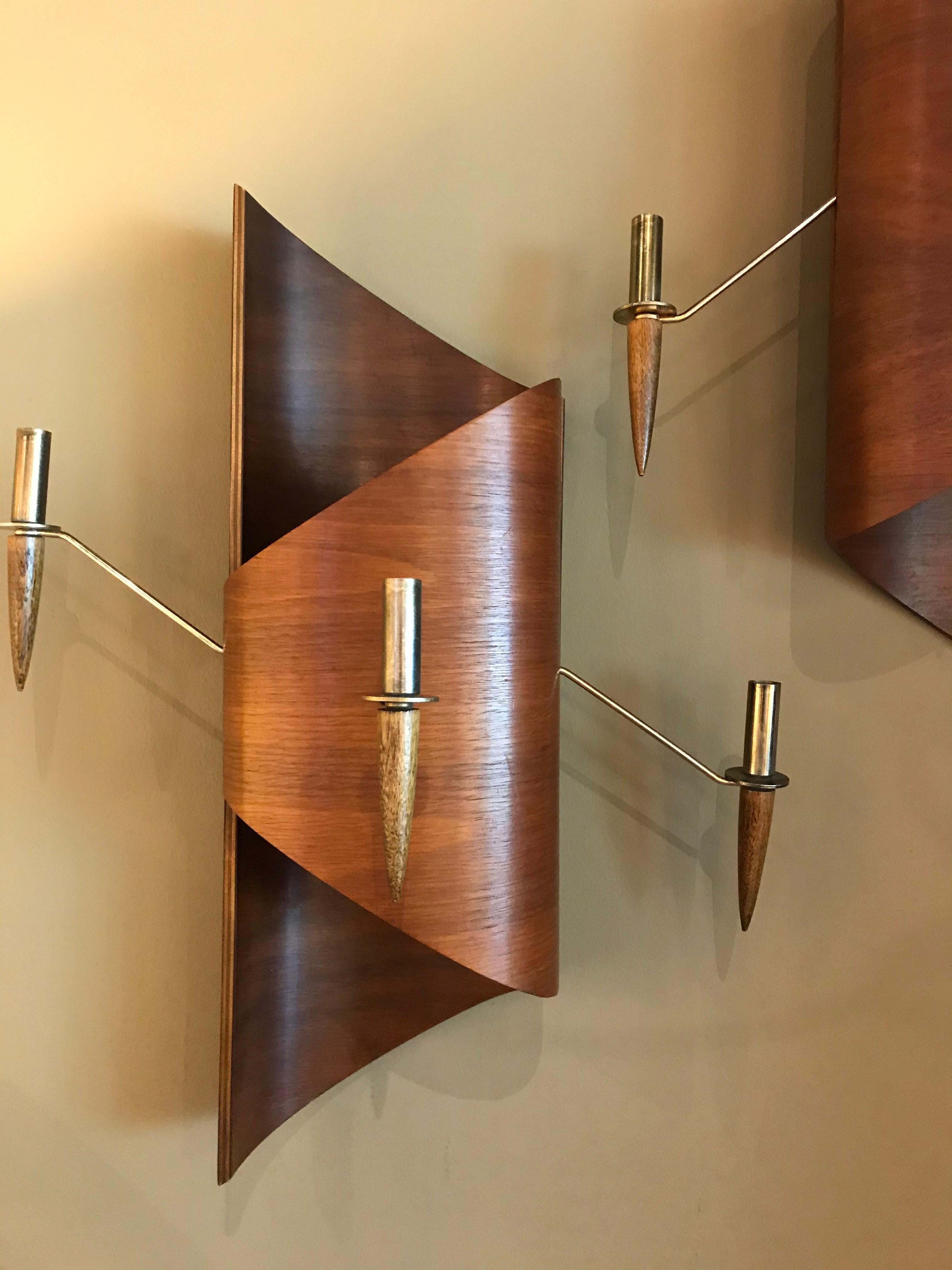 Highly unusual and decorative pair of formed teak midcentury Italian candle sconces. Juxtaposed curled scrolling shapes with brass wire and teak wood candleholders reaching out to the sides and front. Three candleholders each. Screw holes for the