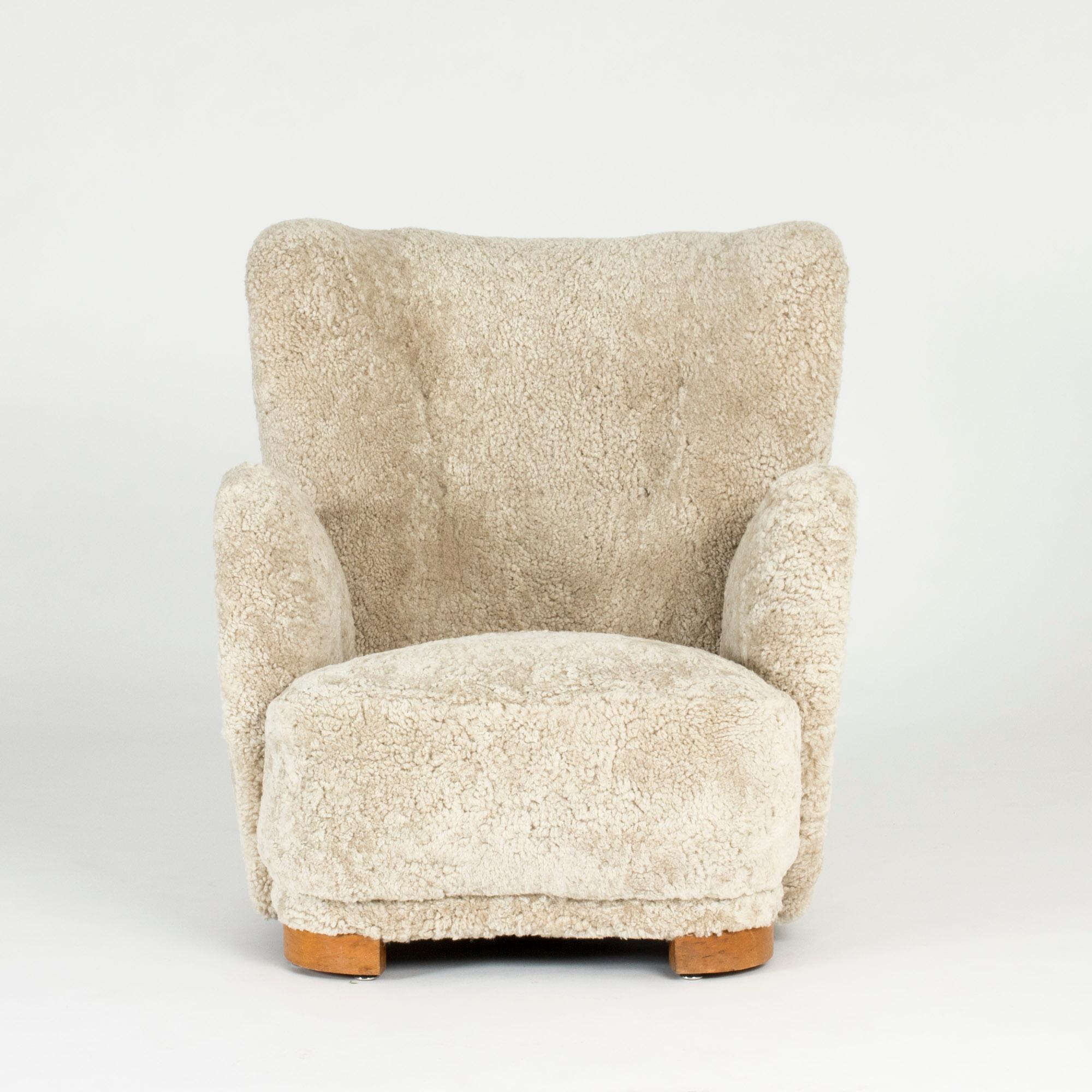 Amazing Danish, 1930s lounge chair in the style of Flemming Lassen, upholstered with cream colored sheepskin. Voluptuous shape and bold lines, a perfect cocoon.