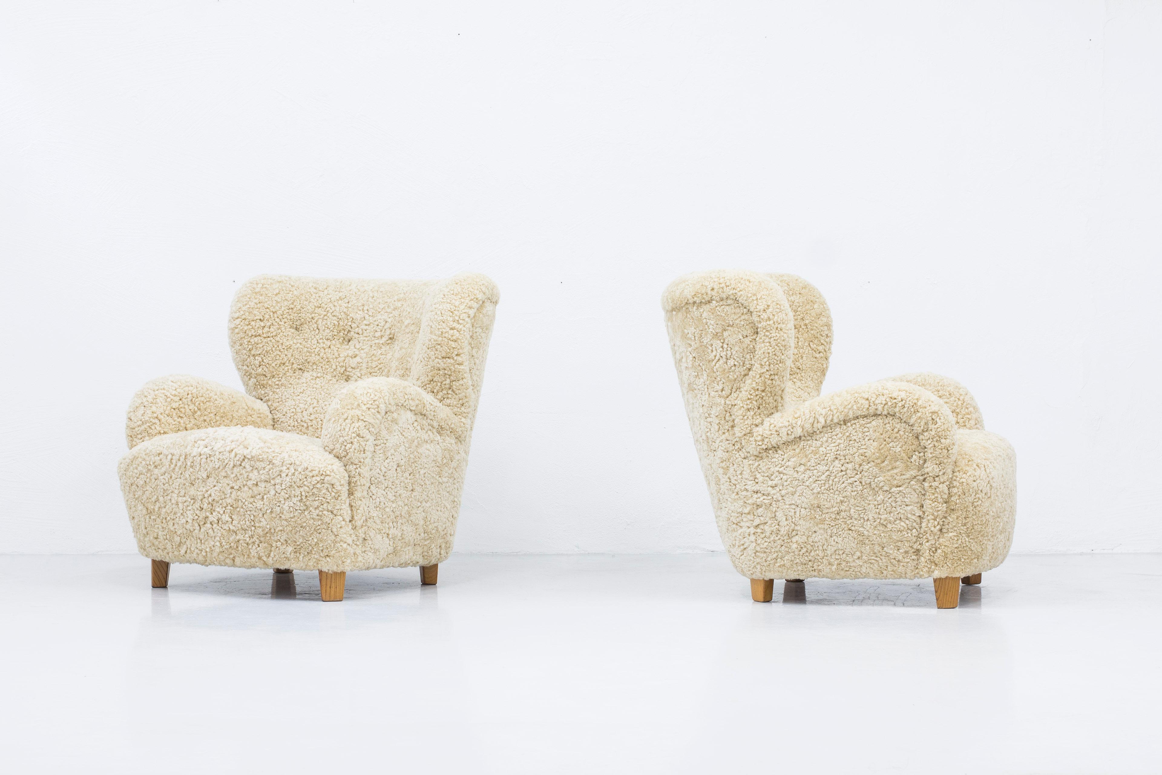 Danish modern lounge chairs similar to the style of Flemming Lassen. Produced in Denmark during the 1930-40s. Solid elm feet and new upholstery in sheepskin/shearling in a light beige color. Beautiful organic lines and excellent quality. Upholstery
