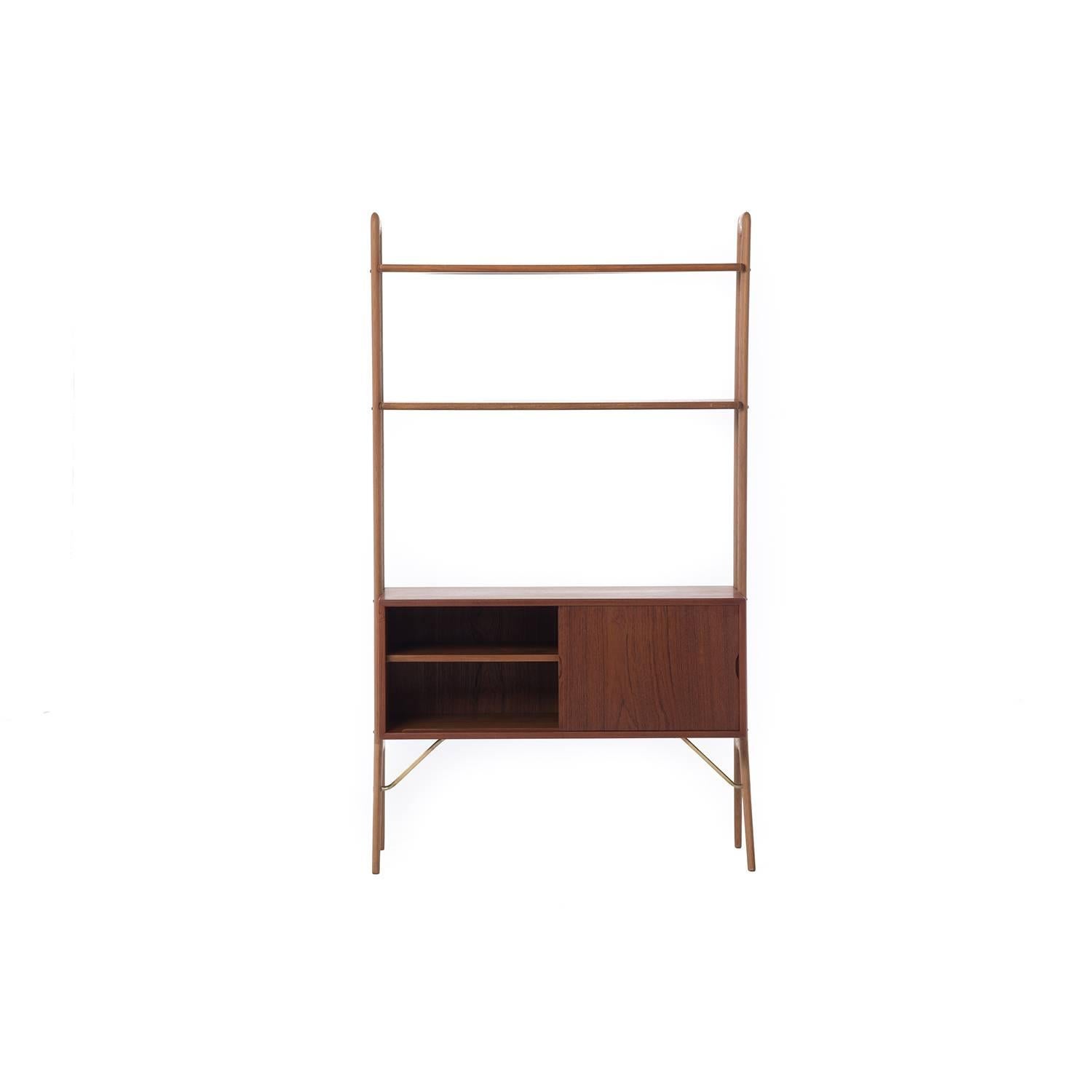 This Kurt Ostervig shelving unit features oak legs, a fixed teak cabinet, and adjustable teak shelves. Brass hardware.