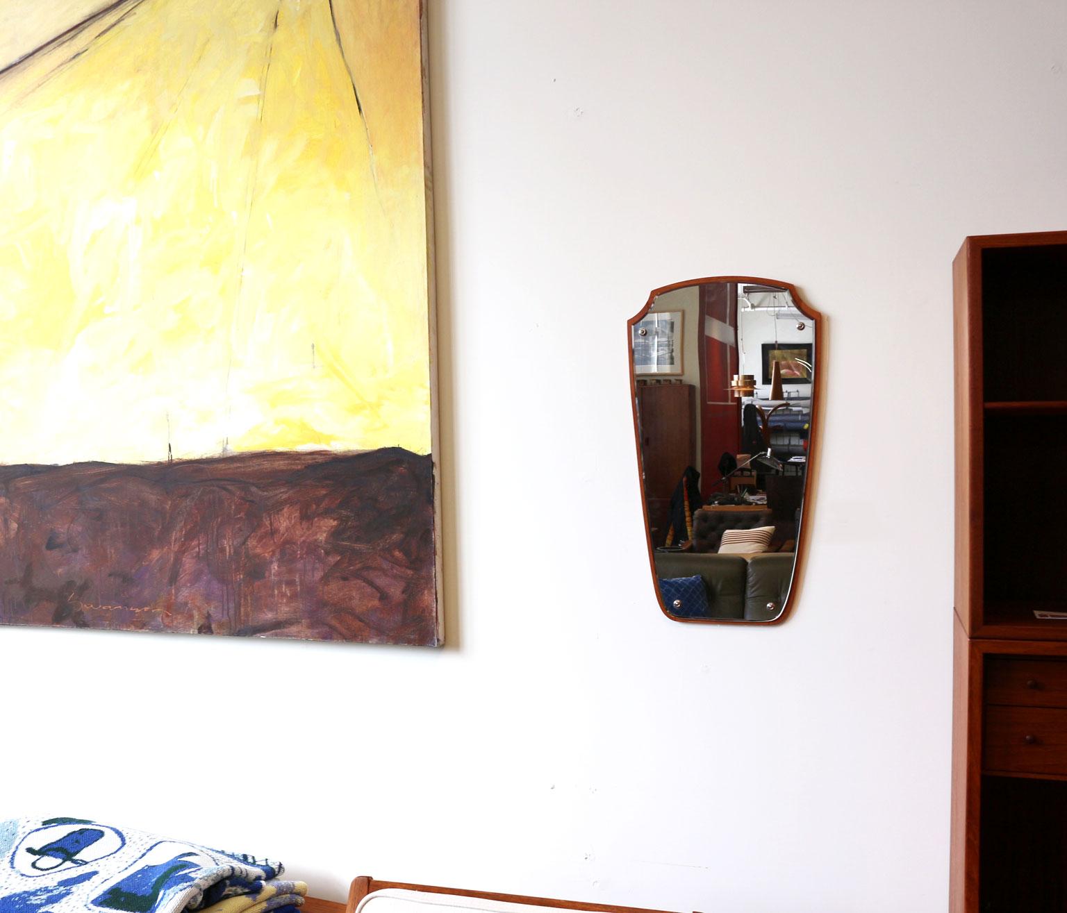 Small spaces always look bigger when you put a mirror on the wall; a mirror like this shield shaped Danish modern teak mirror.