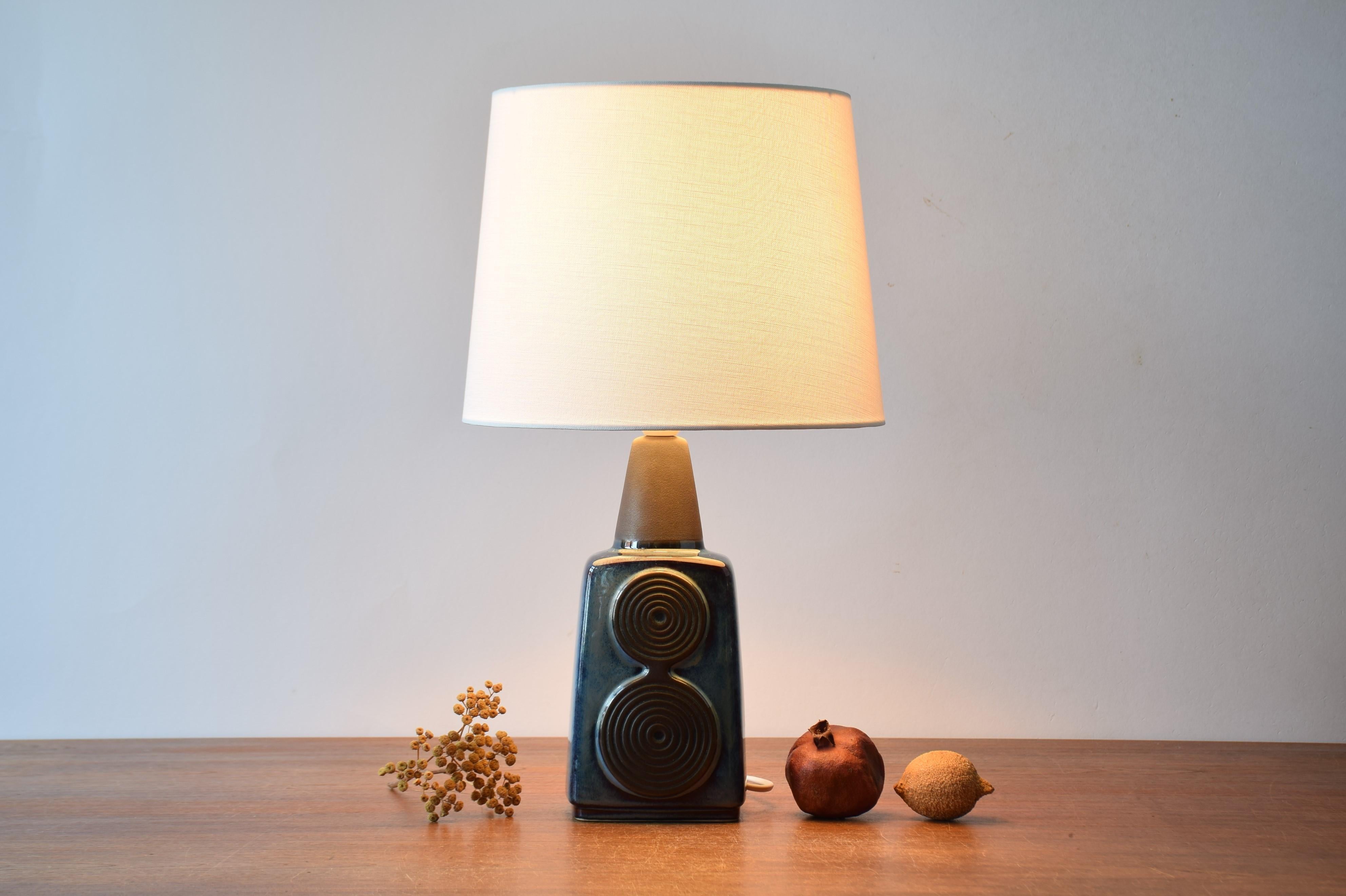 Table lamp by Einar Johansen for Søholm Stentøj, Denmark, circa 1960s.
The lamp has shiny blue glaze with raised circle decors and neck in matte black. 

Included is a new lamp shade designed and made in Denmark. It is made of woven fabric with
